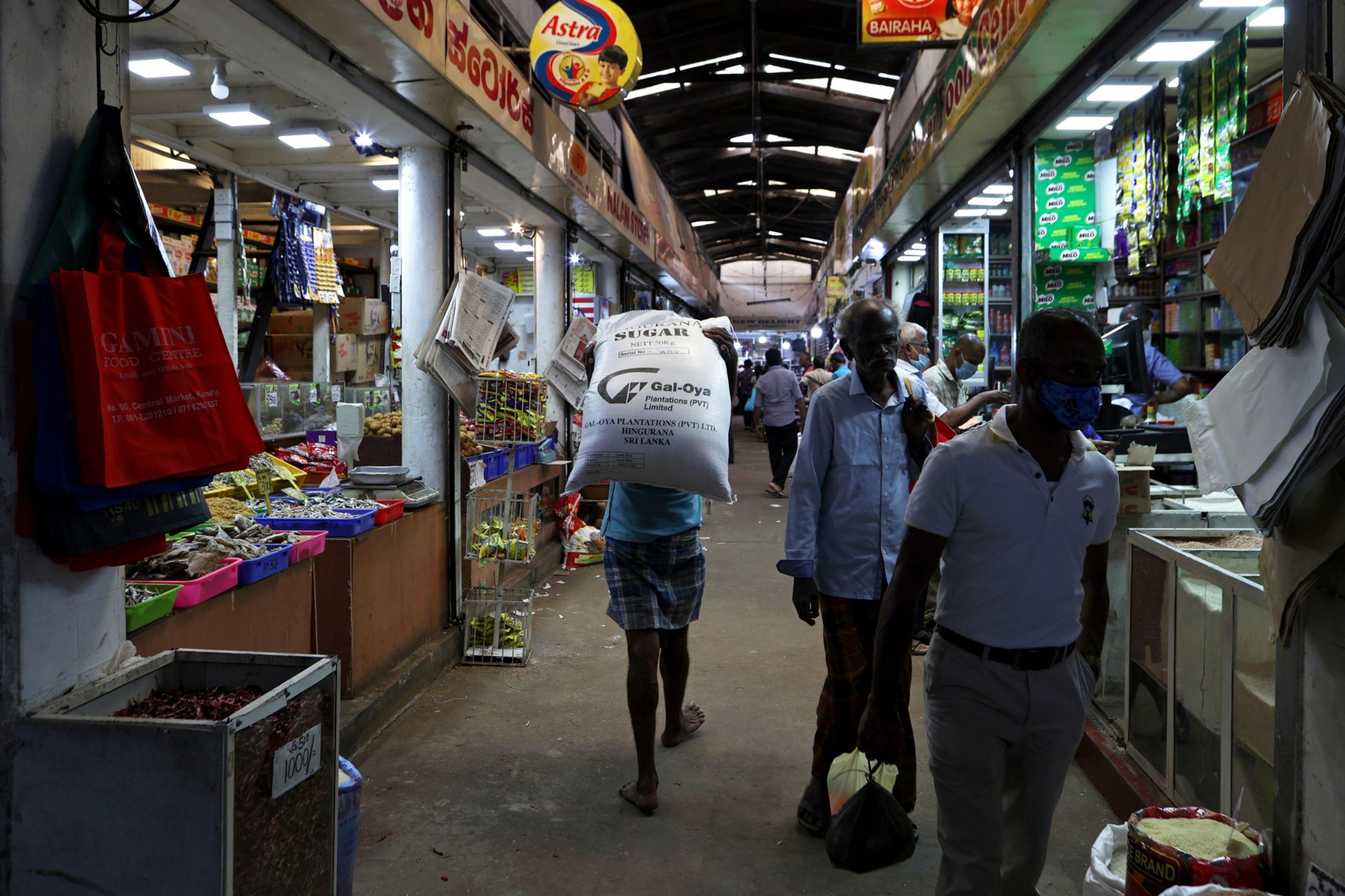 A worker carries a sack of sugar in a market in Kandy, Sri Lanka