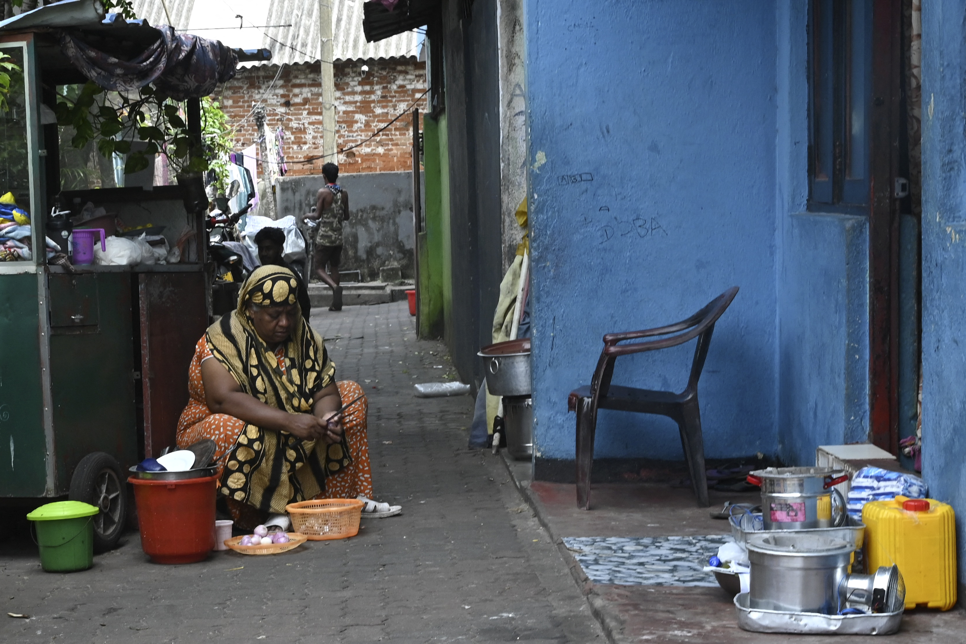 a woman peeling onions in an alleyway