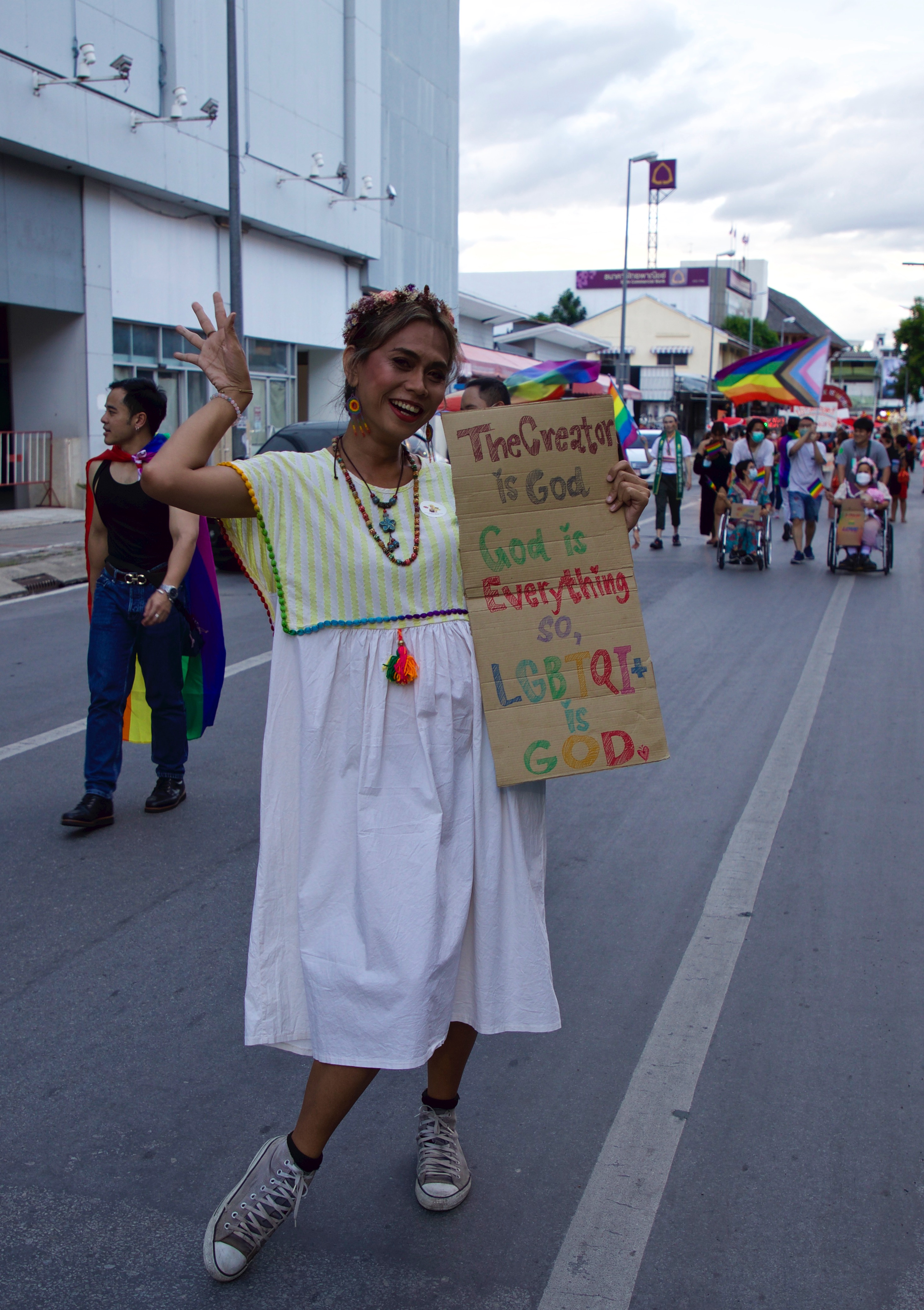 A Pride participant holds a handwritten placard saying: 'The creator is God. God is everything so LGBTQI+ is GOD'