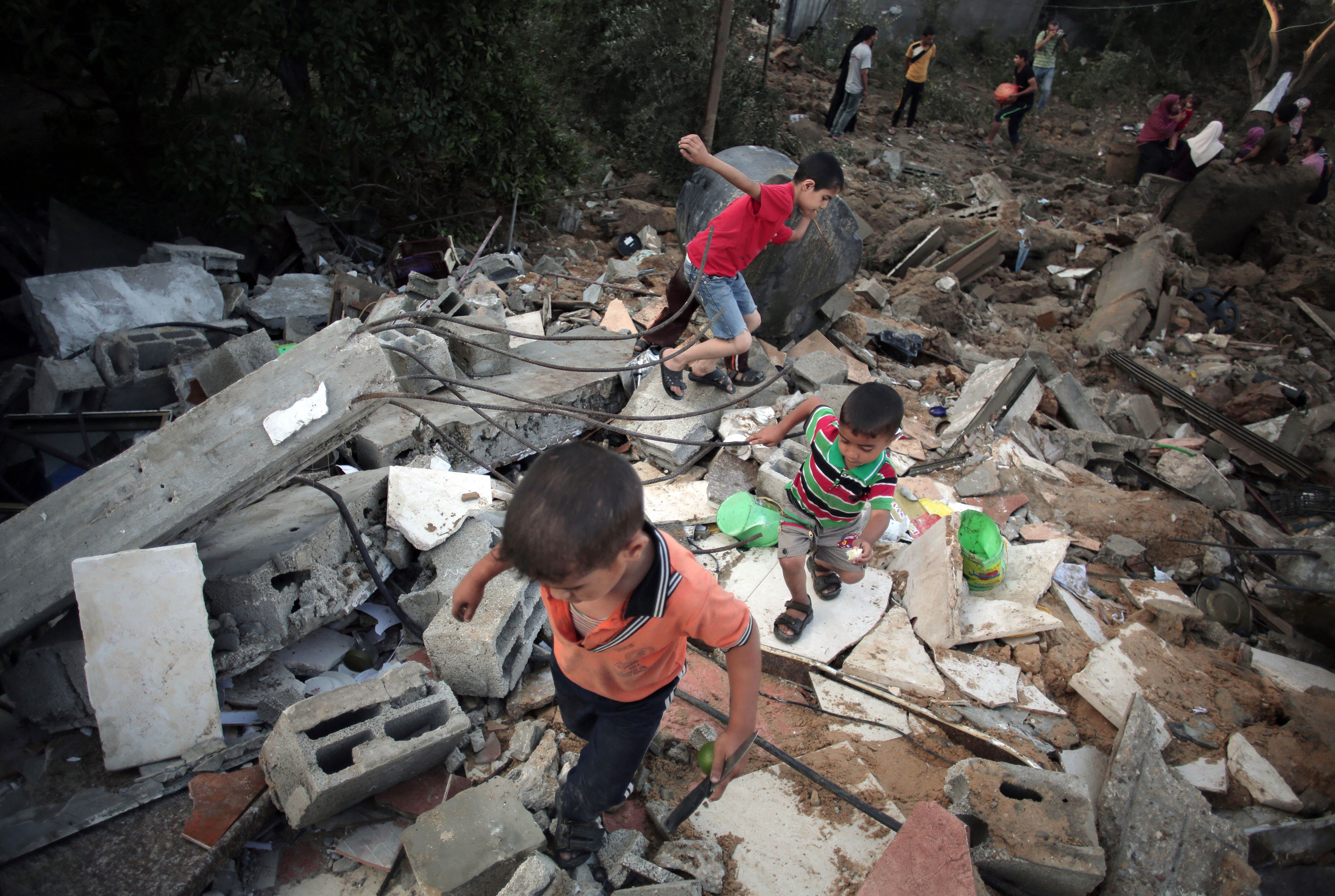Palestinian children walk in the rubble of a house destroyed by an Israeli strike, in the town of Beit Hanoun, northern Gaza Strip in 2014