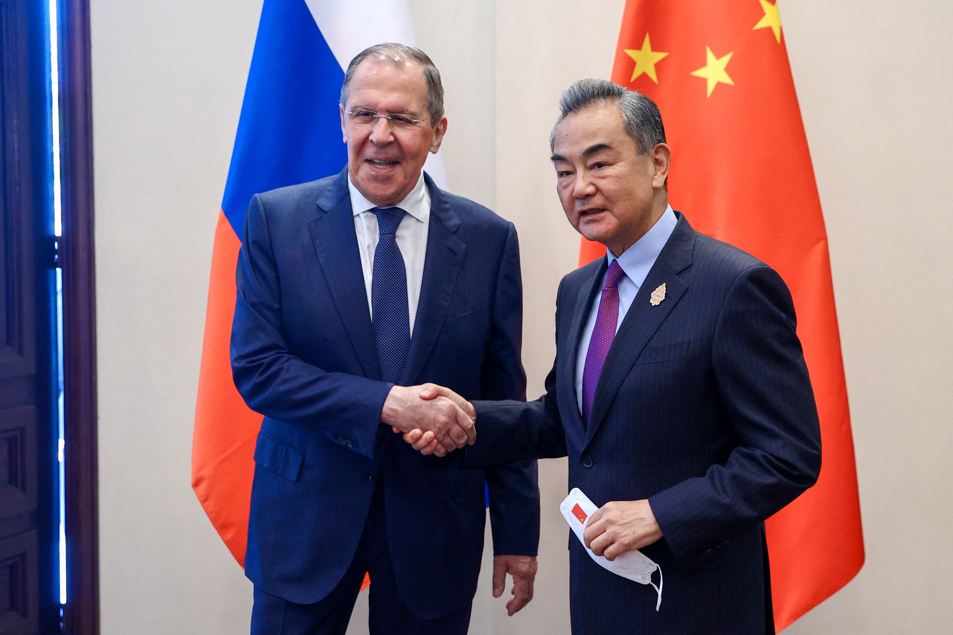 Russian Foreign Minister Sergey Lavrov and Chinese Foreign Minister Wang Yi shake hands as they meet in Denpasar, Indonesia