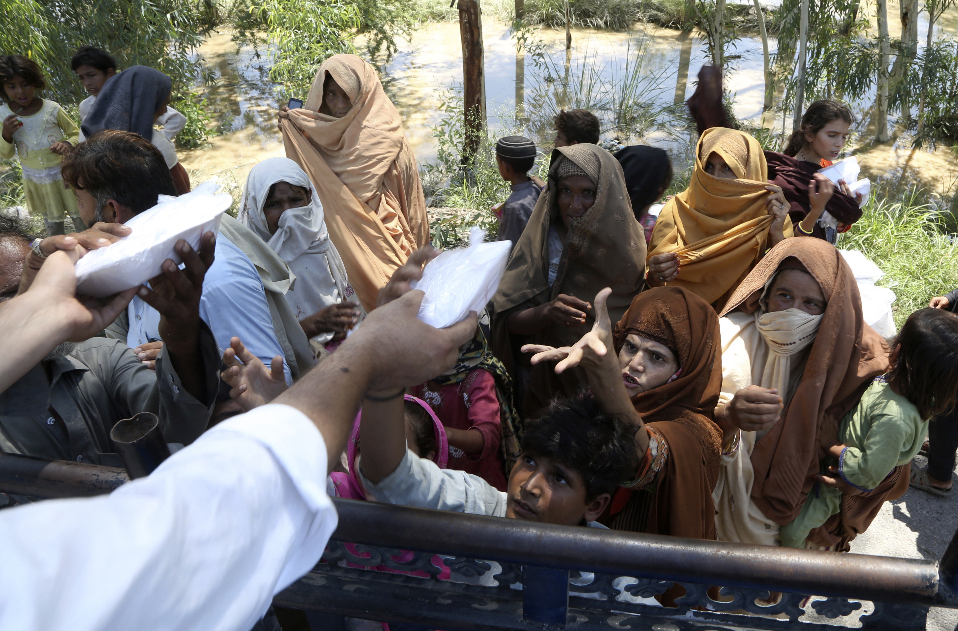 Displaced families receive food and take refuge on a roadside in Peshawar.