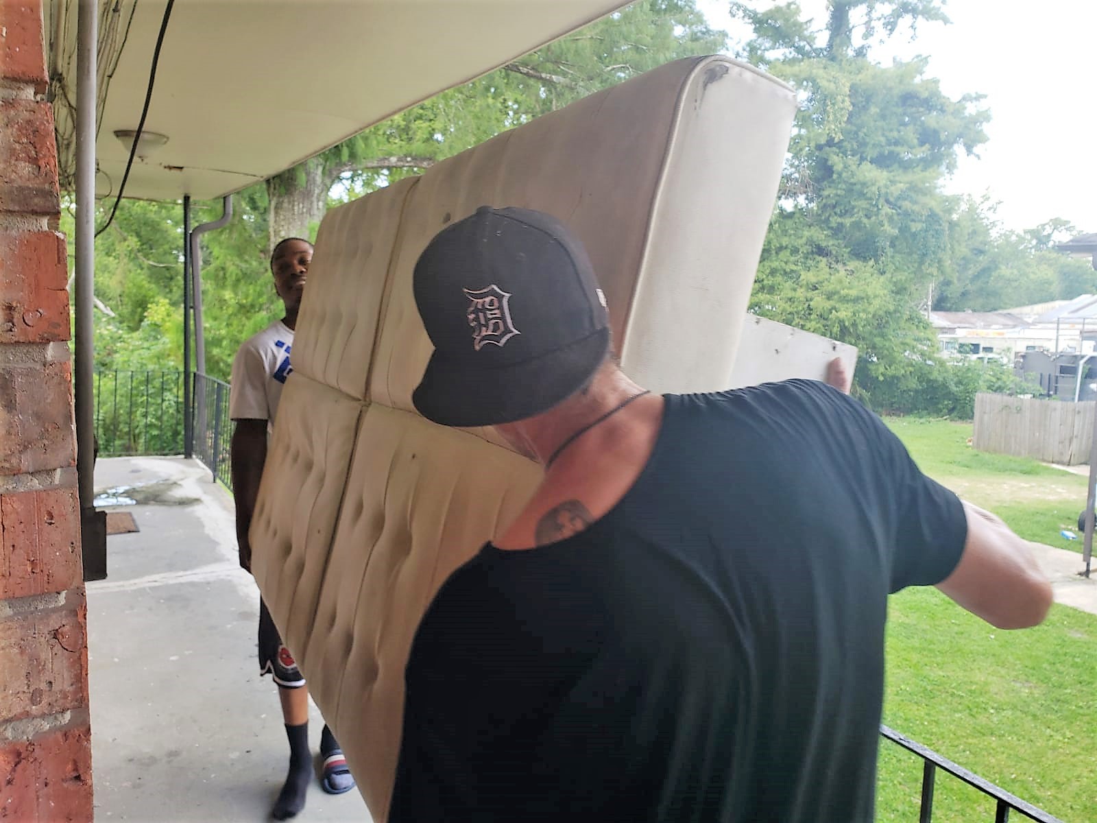 Terry holding one end of a matrass and someone else holding the other side as they carry it along the landing.