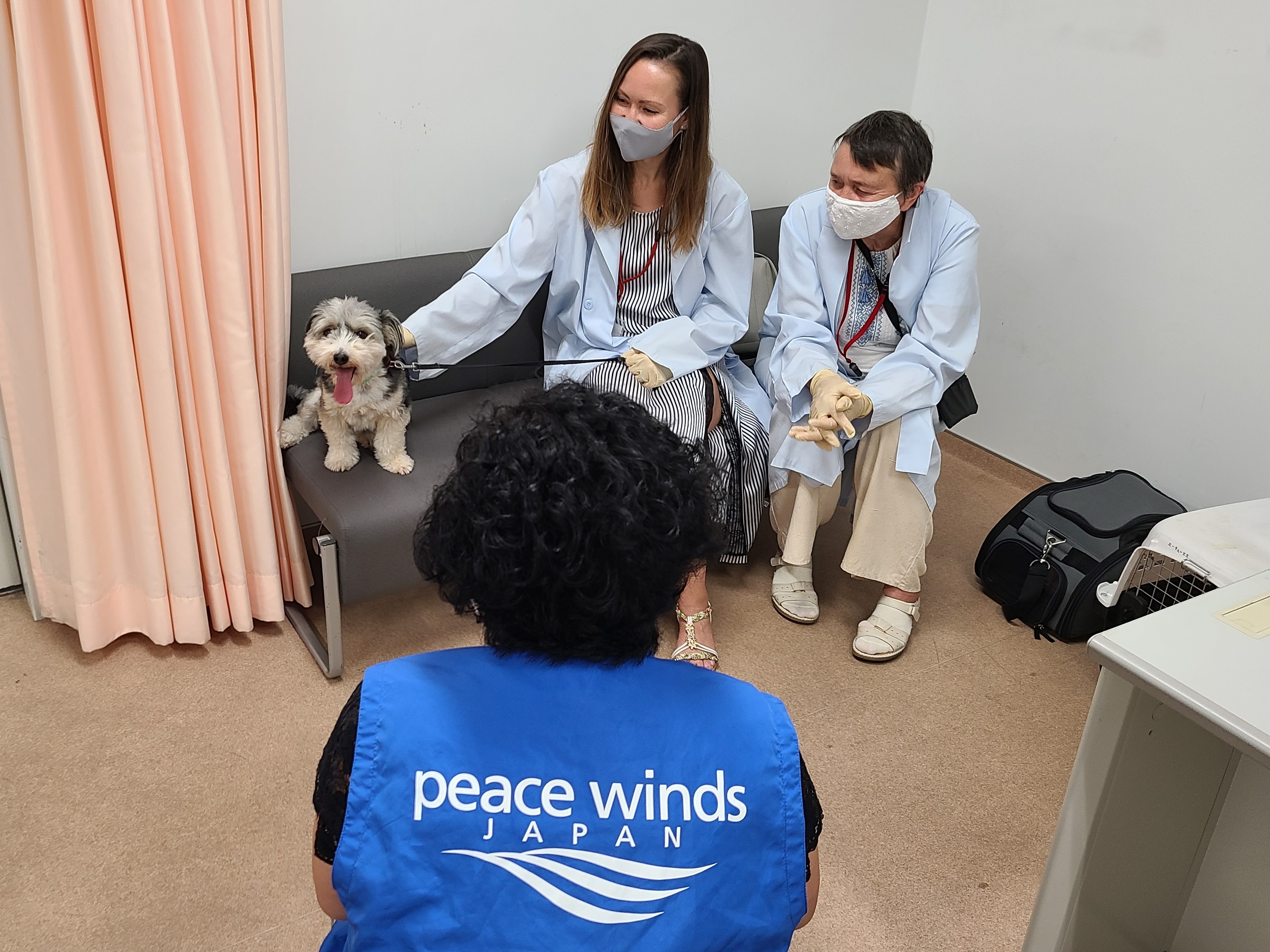 Two women sit on a sofa with a dog at Peace Winds Japan