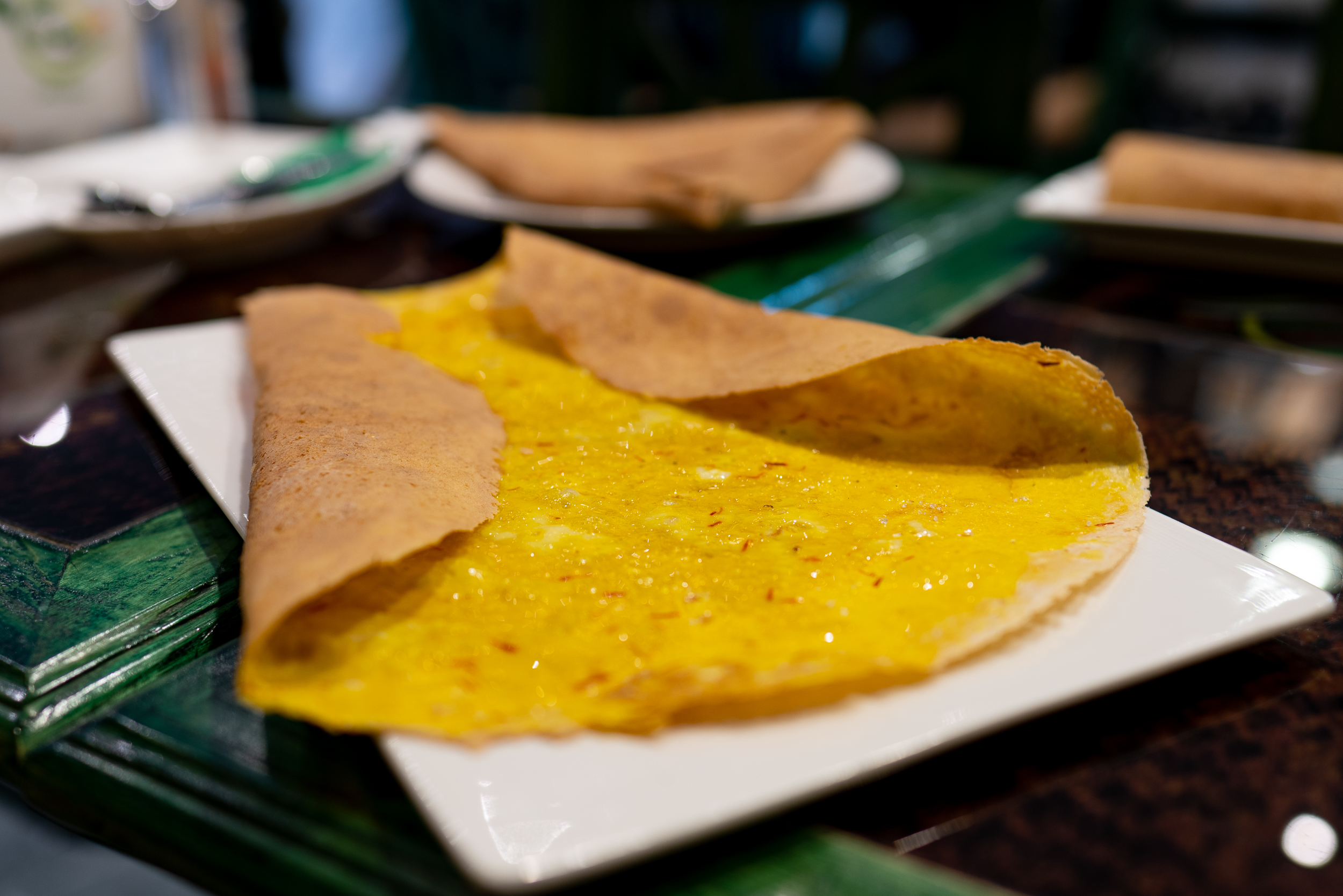 A regag bread with the sides folded in partway to make a rough triangular shape (the top of the triangle isn't closed) shows the rich yellow egg filling with strands of saffron floating on top