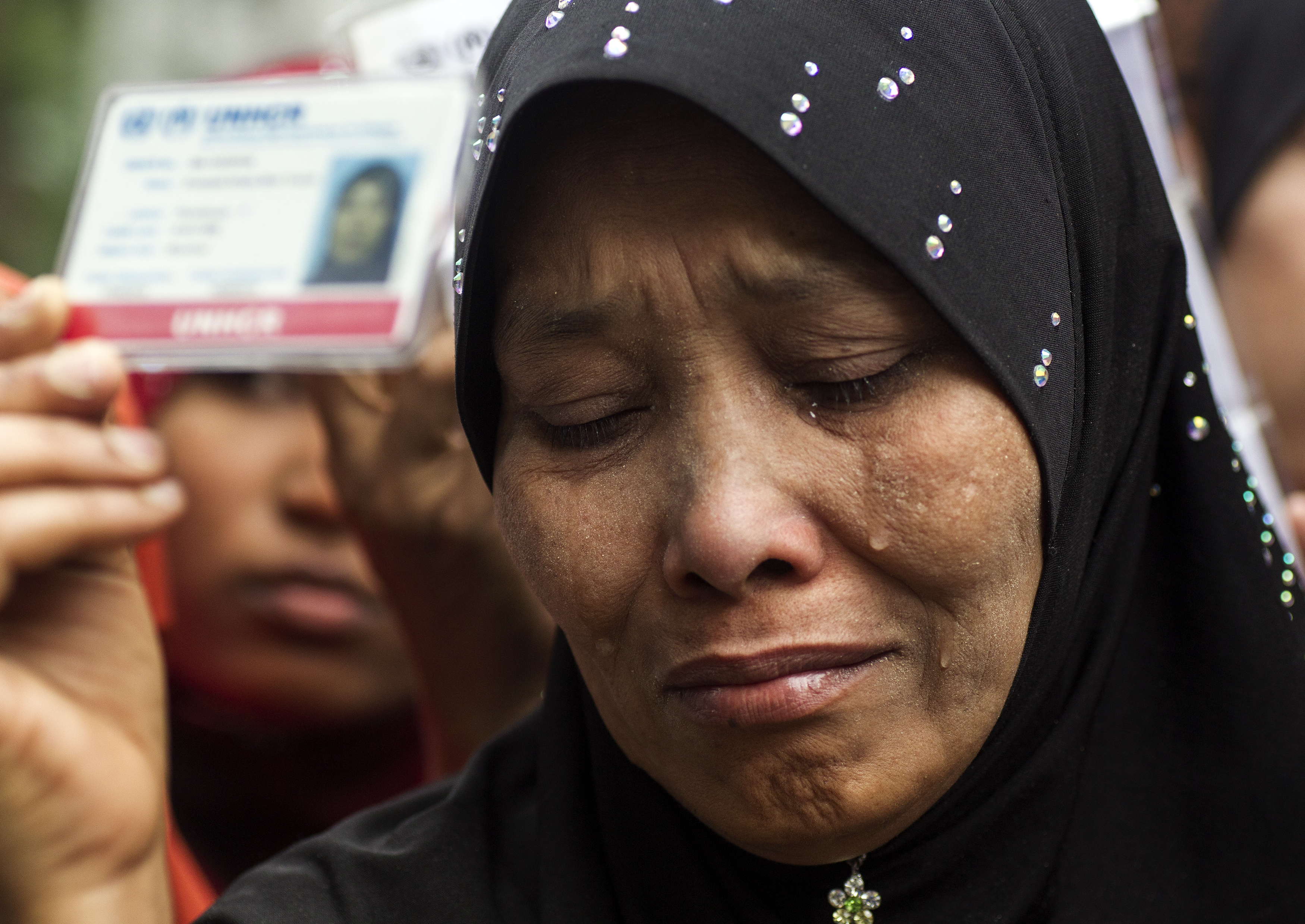 A Rohingya woman in a headscarf holds her the card given to her by UNHCR