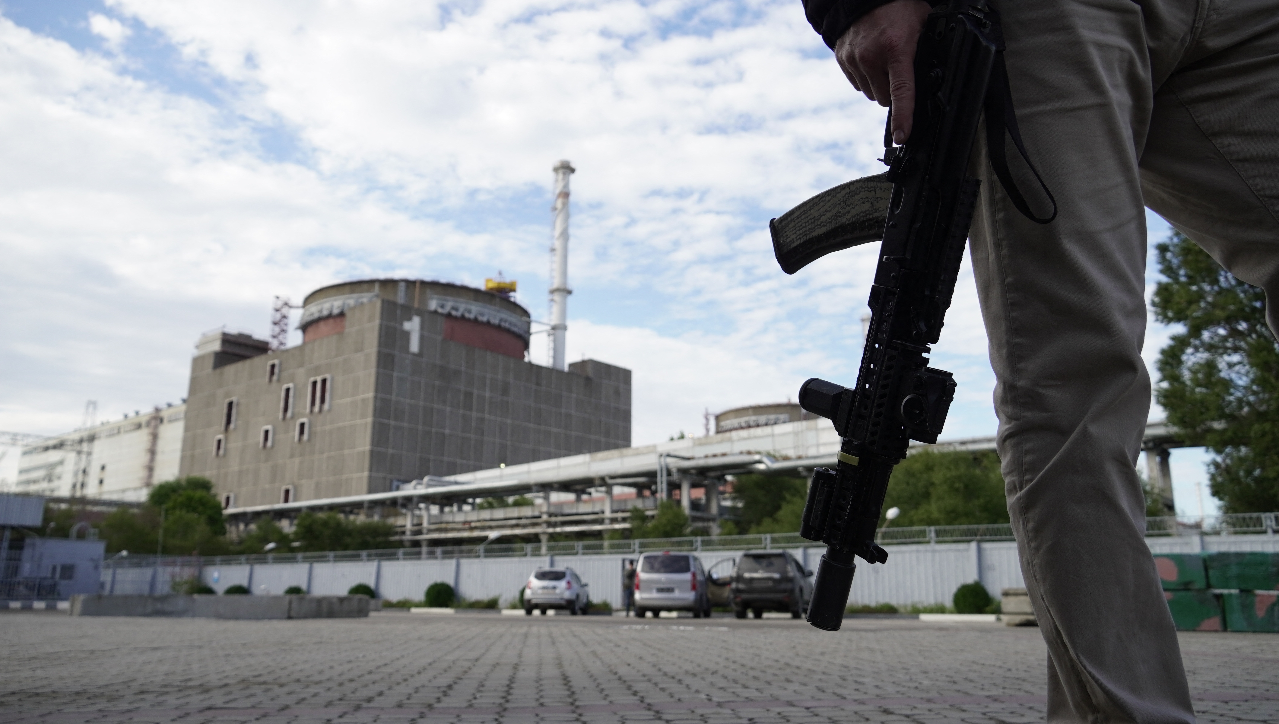 A security person, with a weapon by his side, stands in front of the Zaporizhzhia Nuclear Power Plant in Enerhodar, Zaporizhia Oblast.