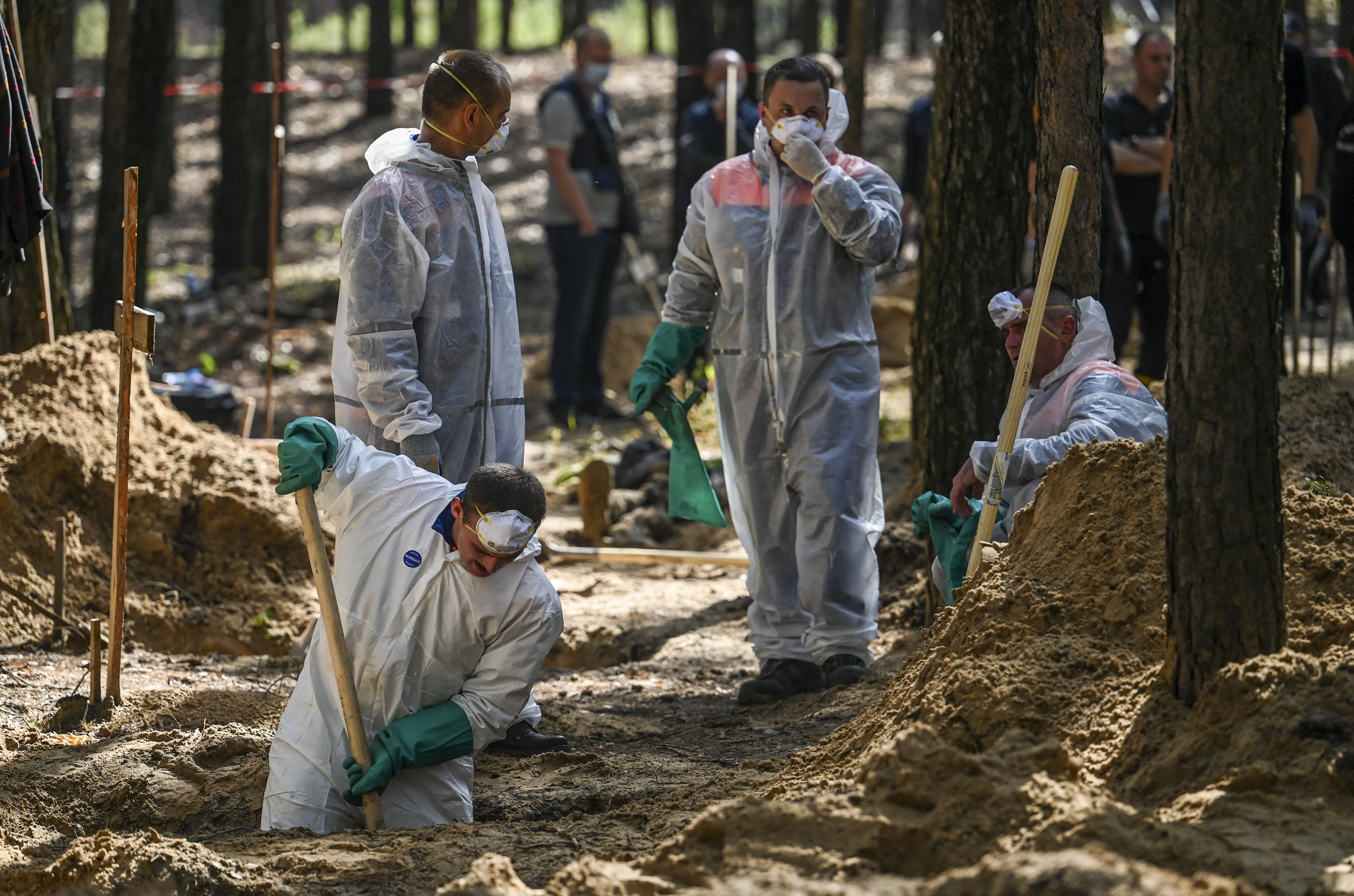 Forensic technicians dig at the site of a mass grave in a forest on the outskirts of Izyum