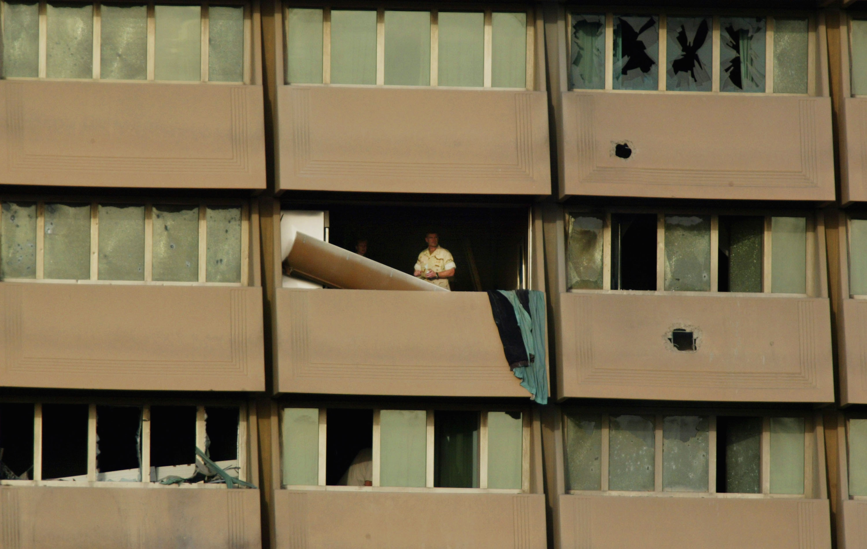 A US soldier looks out of his hotel room amid blown-out windows after rockets were fired at the hotel on the morning of October 26, 2003