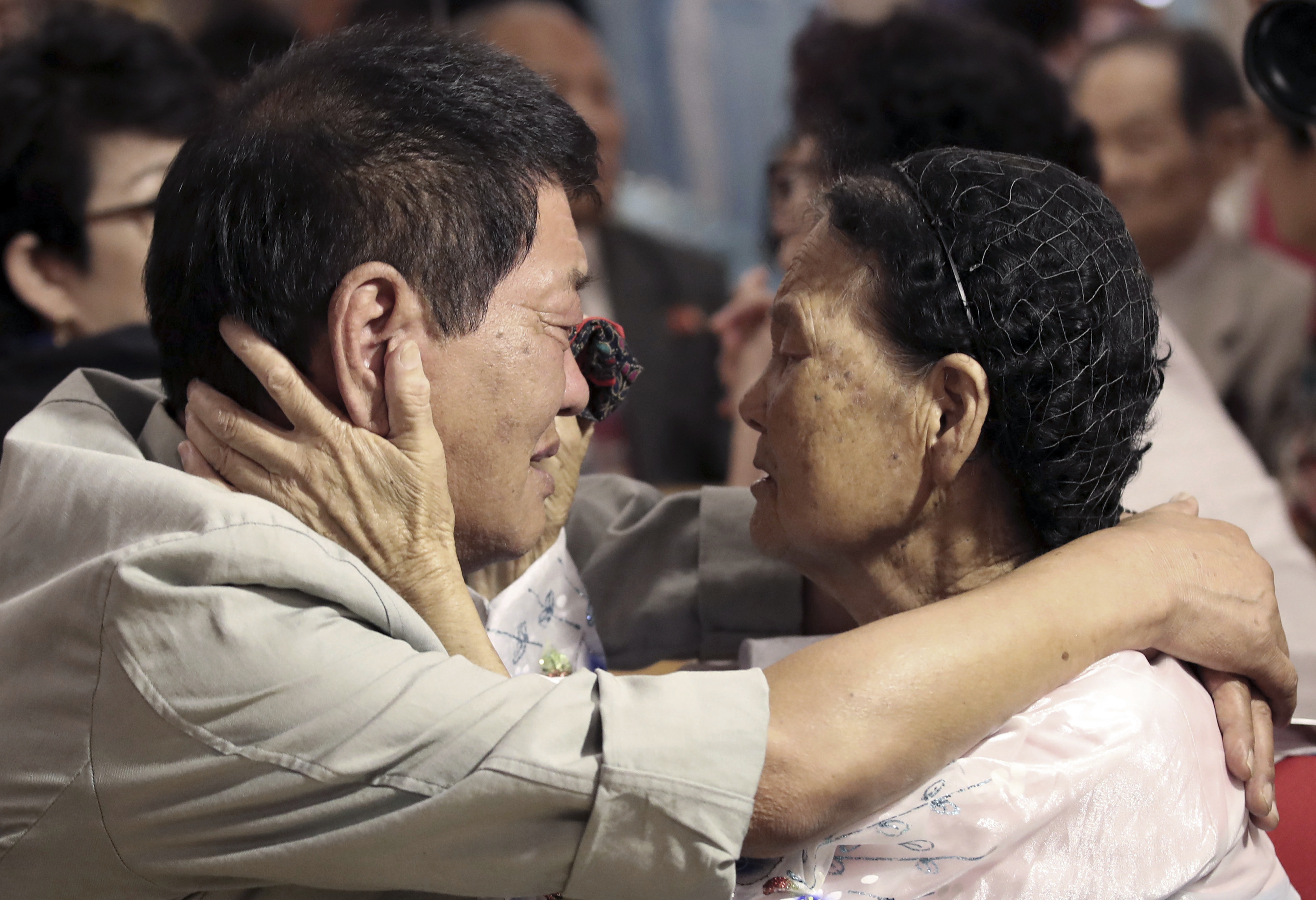 A brother and sister separated by the Korean War look into each other's eyes as she holds her brother's face during a brief 2018 reunion.