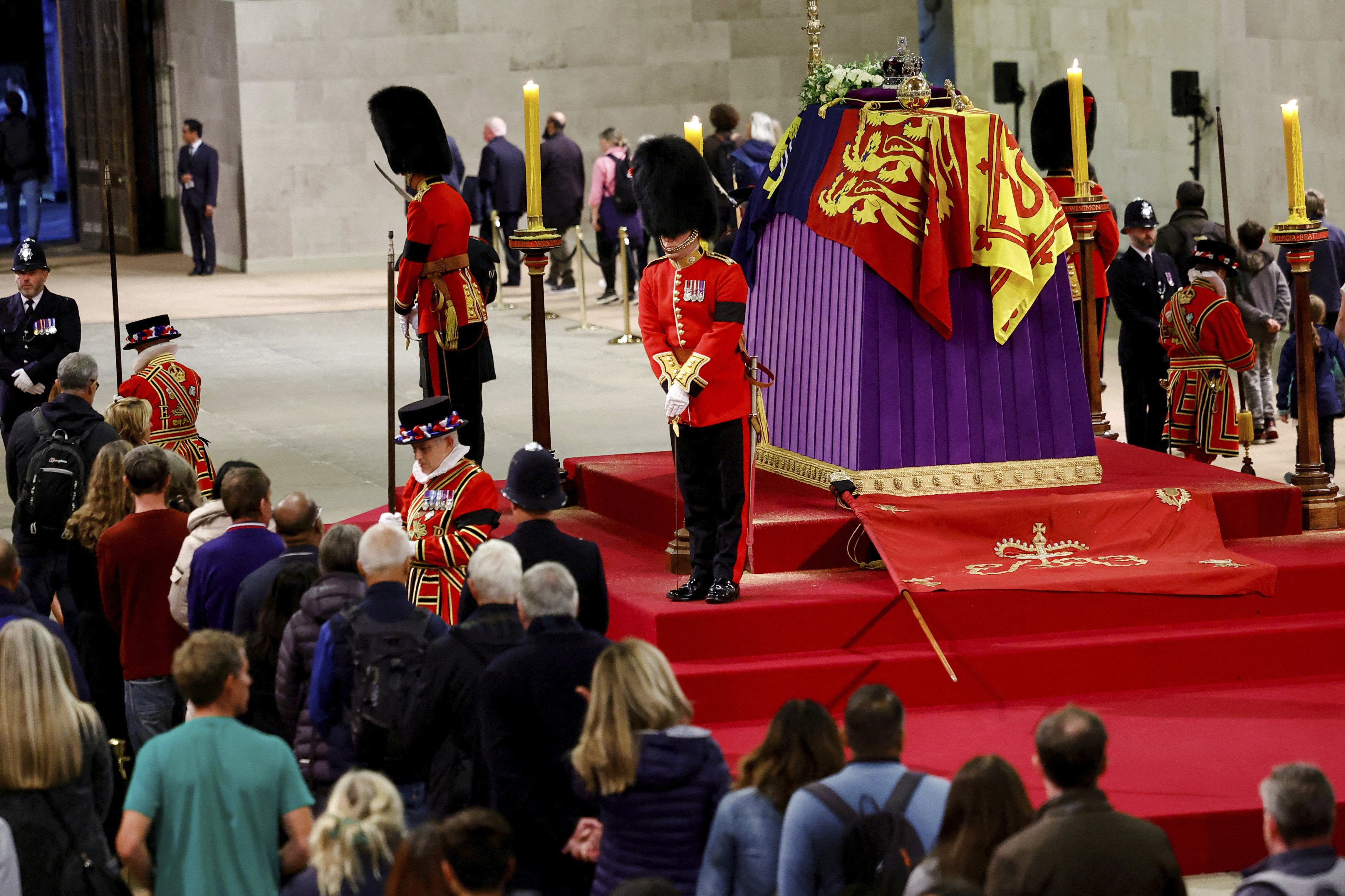 Members of the public walking past the queen's coffin with soldiers in ceremonial dress and bearskin hats standing guard