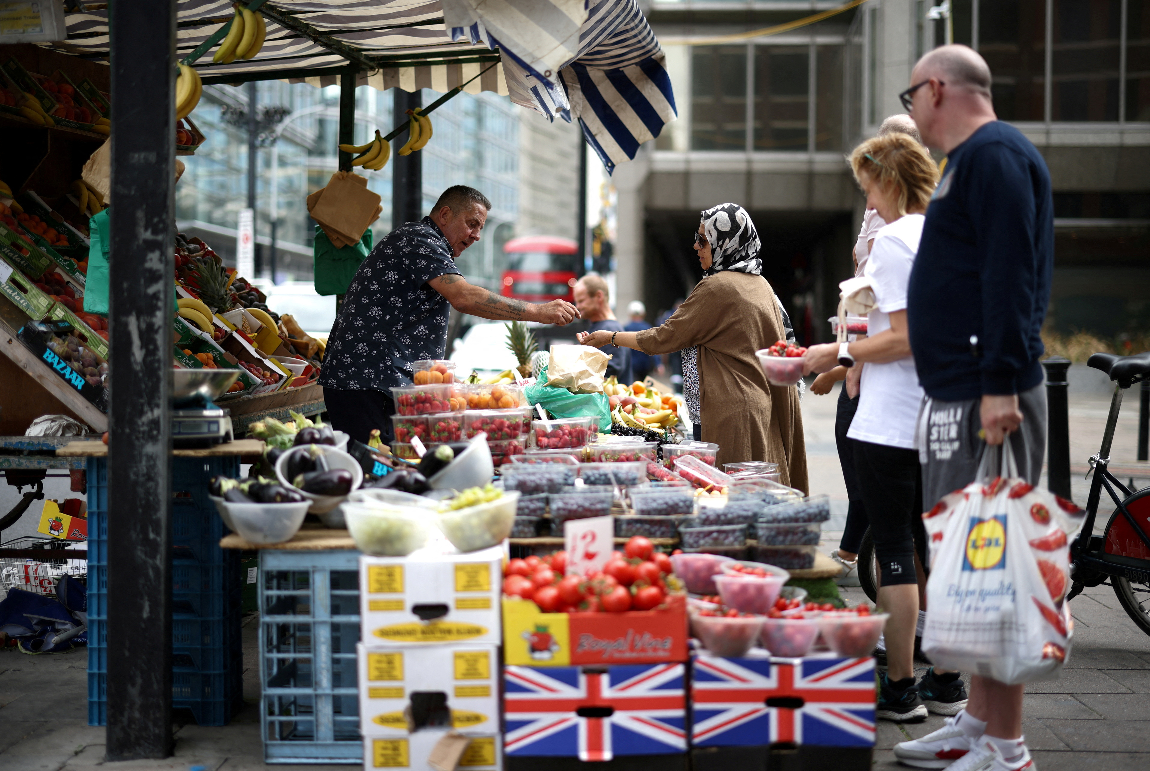 A person buys produce from a fruit and vegetable market stall in central London
