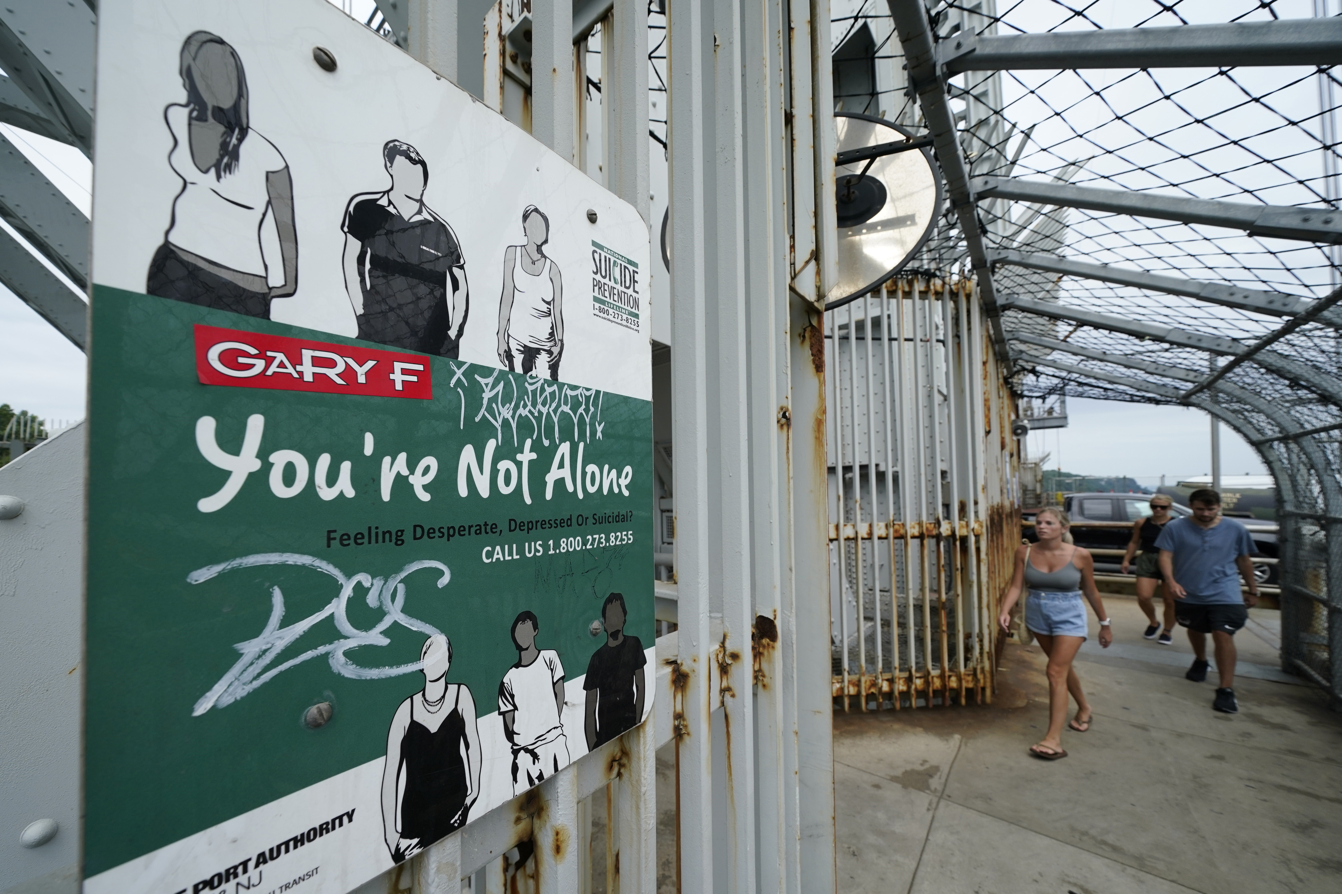 A sign for a suicide prevention hotline is displayed on the pedestrian walkway of the George Washington Bridge in New York