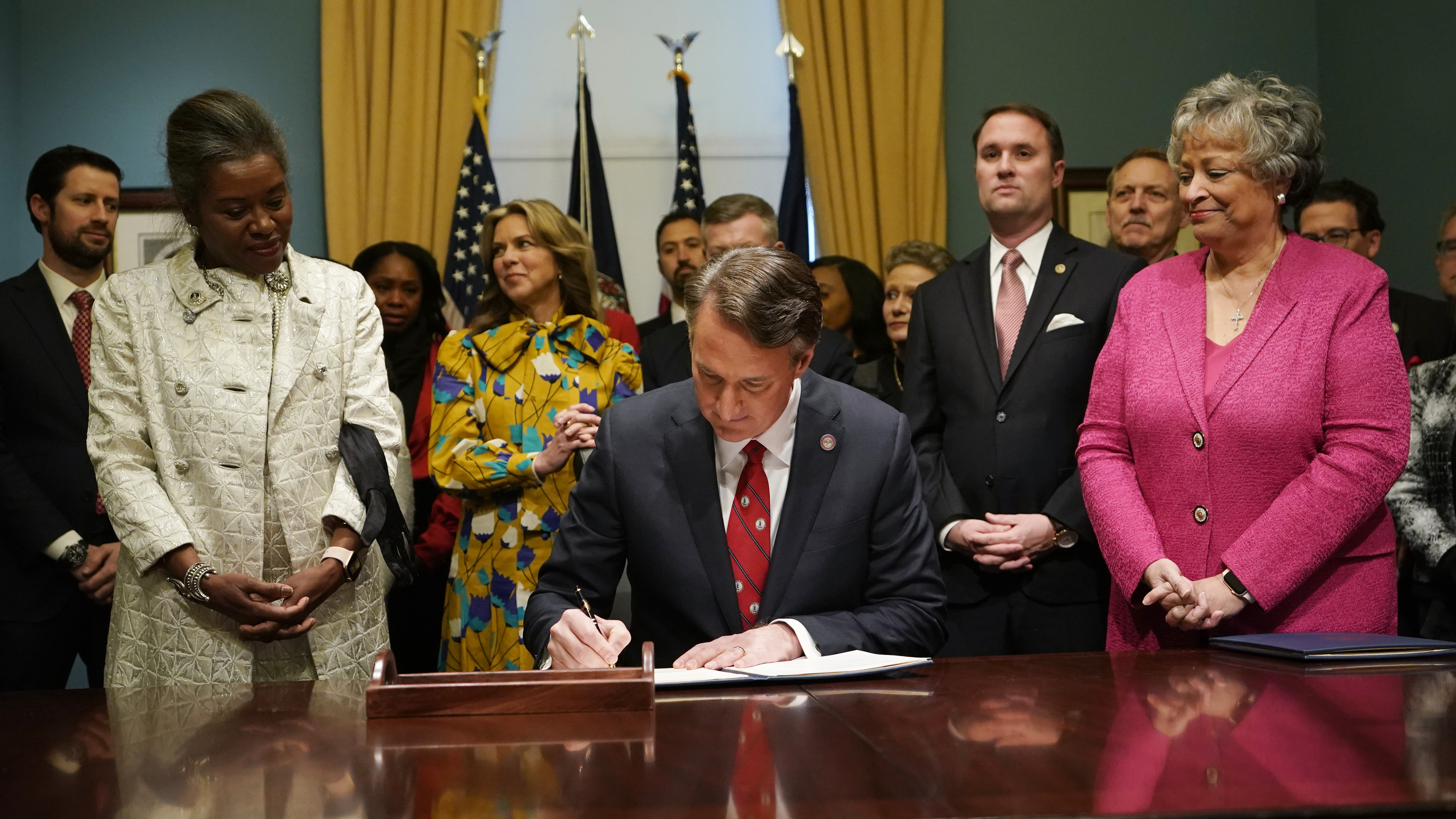 Virginia Gov. Glenn Youngkin, center, signs executive orders in the Governors conference room as Lt. Gov. Winsome Earle-Sears, left, Suzanne Youngkin, second from left, Attorney General Jason Miyares, second from right, and Secretary of the Commonwealth, Kay Cole James, right, look on at the Capitol, Jan. 15, 2022, in Richmond, Va. Virginia's Department of Education is conducting a review designed to root out critical race theory in schools. The review is the first thing Gov. Youngkin ordered after his inauguration and is expected to conclude later this month. Education officials have been reluctant to discuss what they've found thus far. While critics of the governor say critical race theory is a nonissue, others say there is ample evidence that the concepts have been embraced by administrators. (AP Photo/Steve Helber)