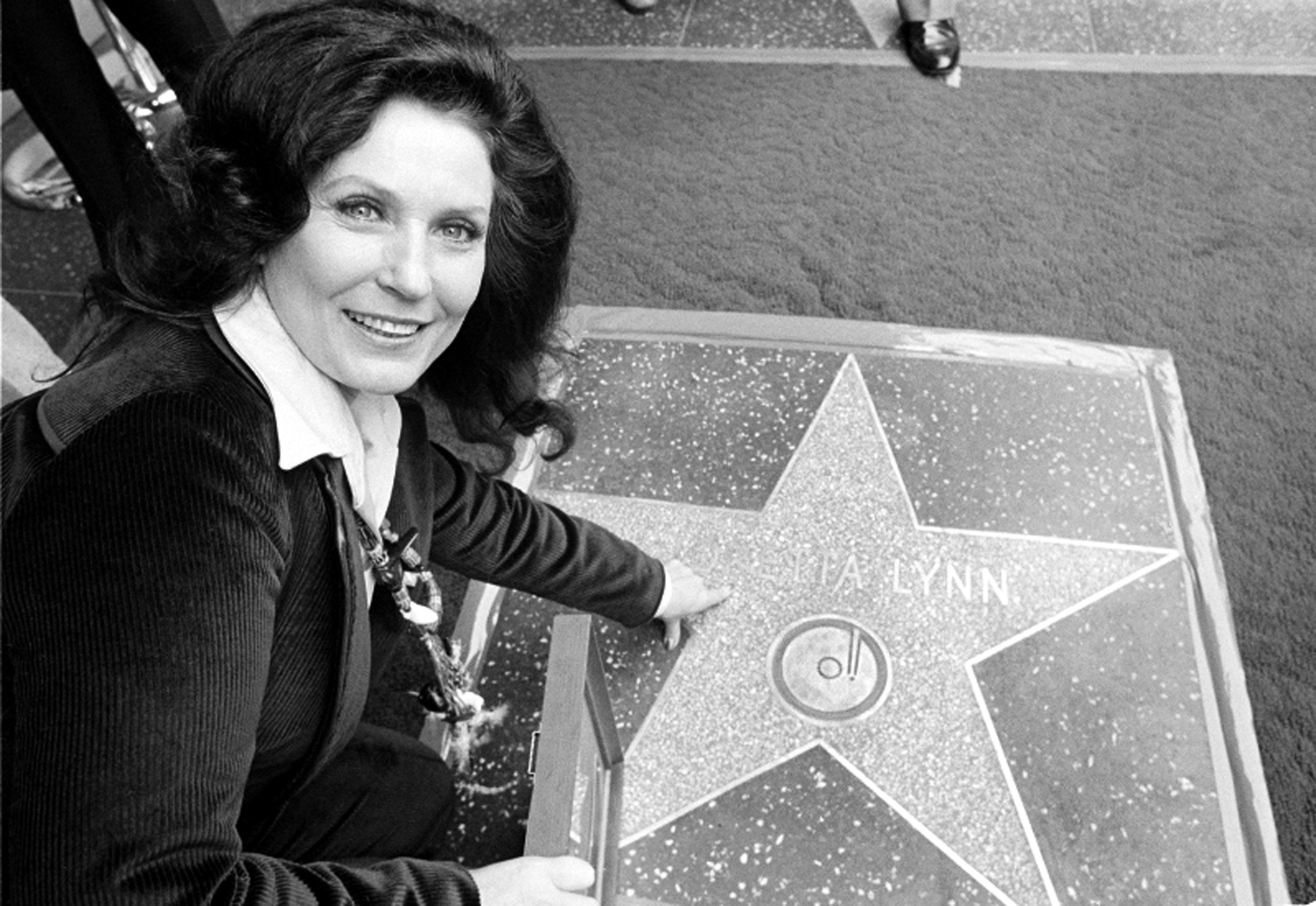 Loretta Lynn posing beside her Hollywood Walk of Fame star during induction ceremonies in Hollywood, California