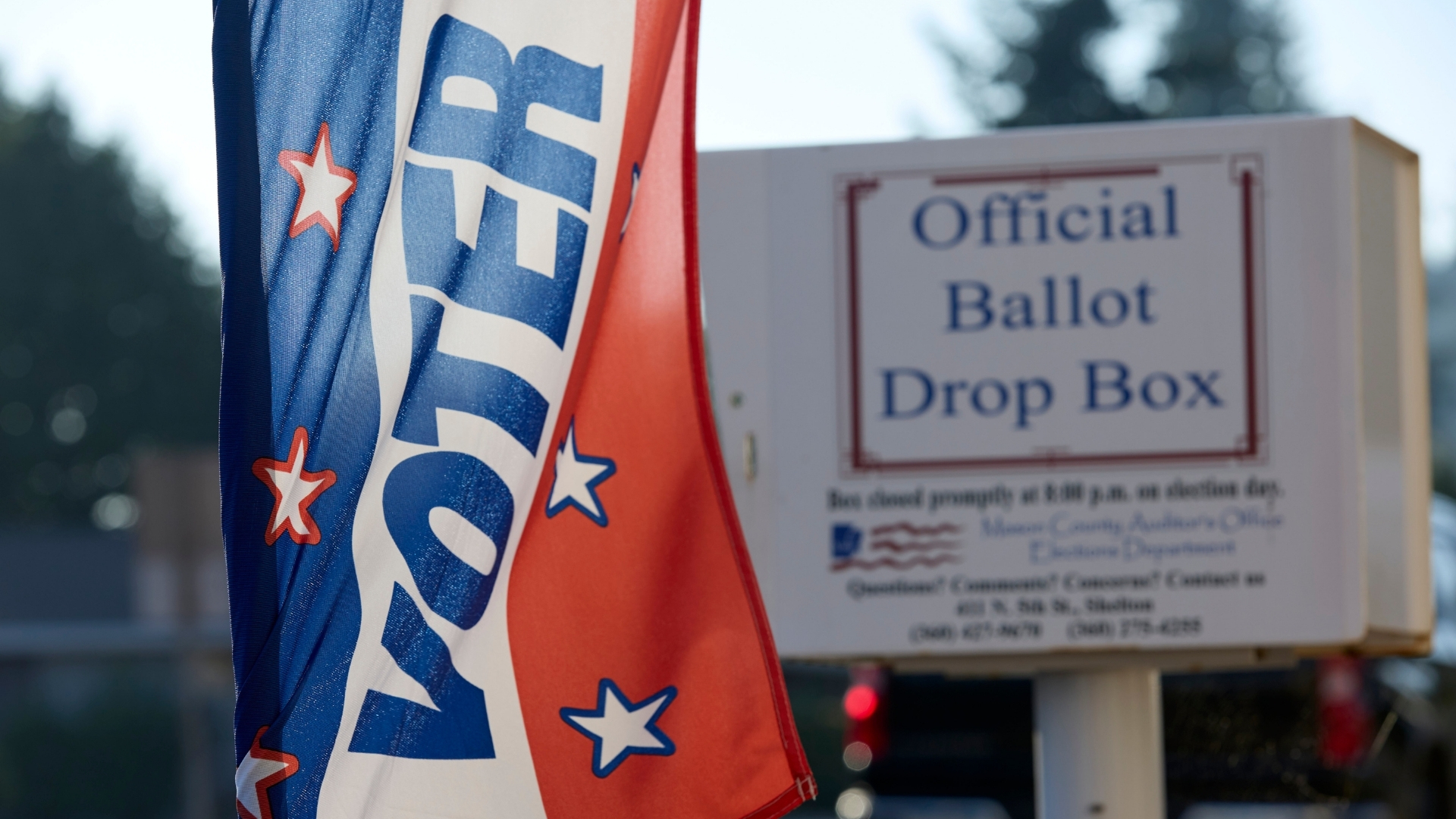 A US flag with the word voter, next to a ballot box