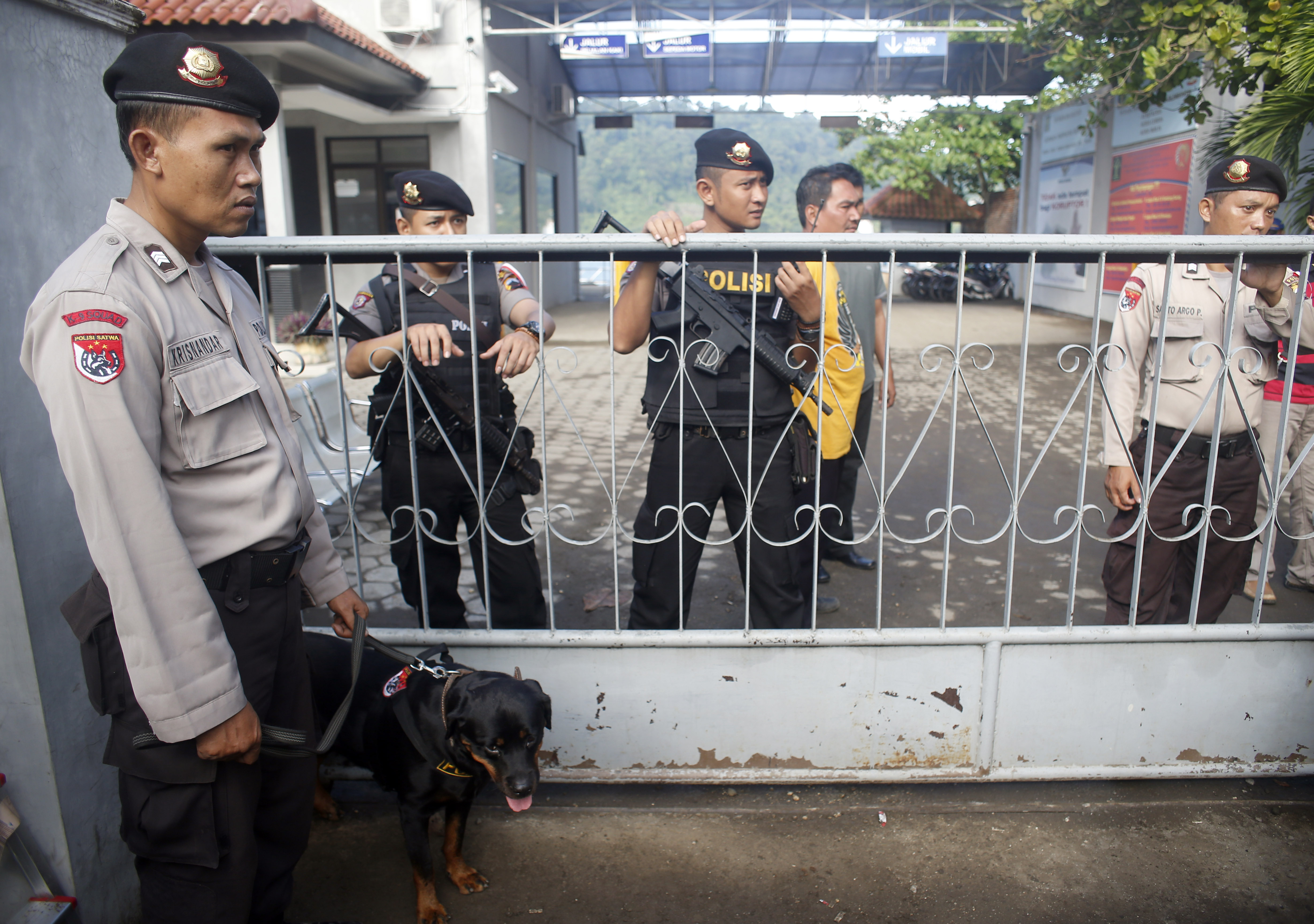 Police and soldiers stand guard behind a metal gate at the port that is the entry point to Indonesia's prison island of Nusakambangan.