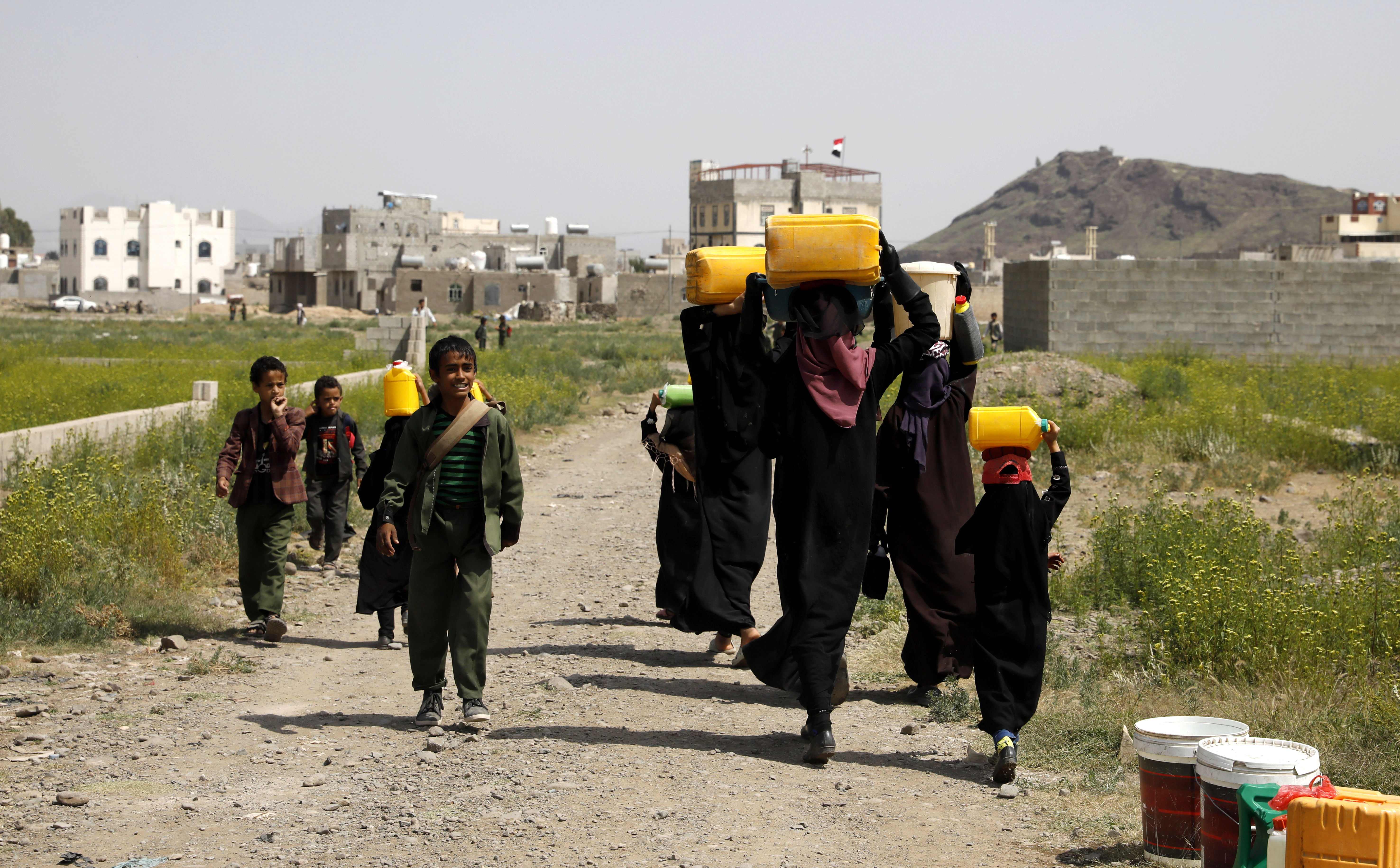 Yemeni boys pass women carrying water jerrycans on their heads after filling them from a donated tank on the outskirts of Sana'a, Yemen, 14 September 2022. Over 17 million people lack access to safe water and adequate sanitation services in war-ravaged Yemen, according to UN estimates. The Arab country is one of the most water-scarce countries in the world. EPA-EFE/YAHYA ARHAB