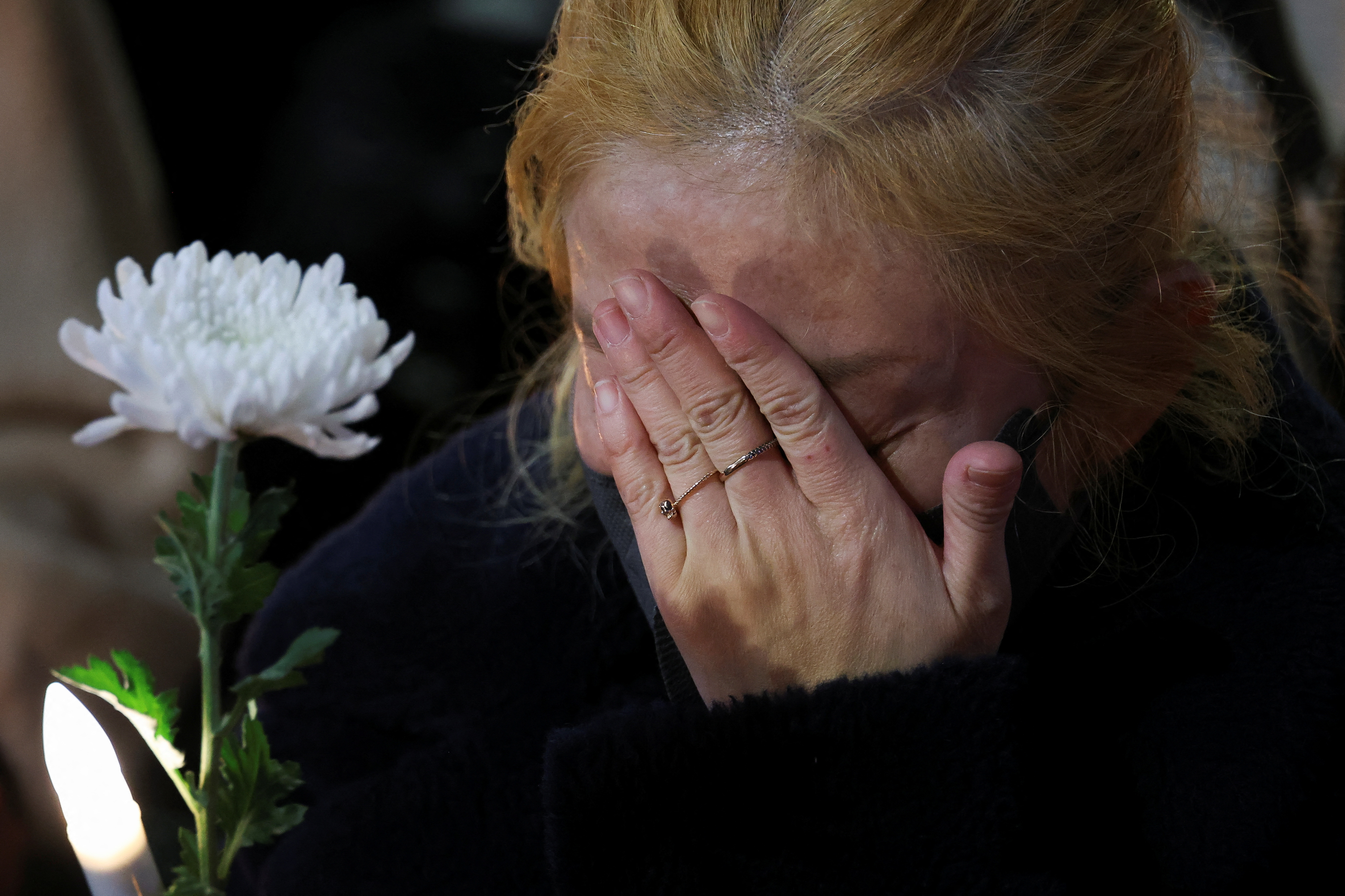 A woman reacts as she attends a candlelight vigil to commemorate the victims of the crowd crush.