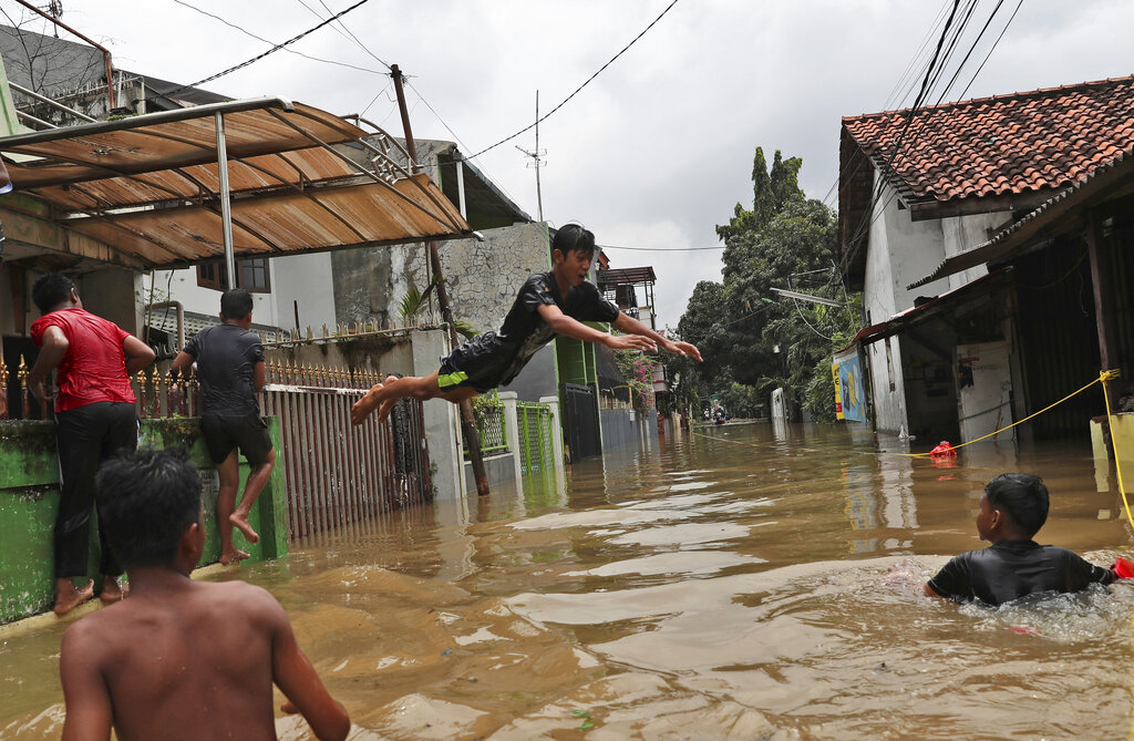 Indonesian youths play in flood water in a Jakarta neighbourhood.