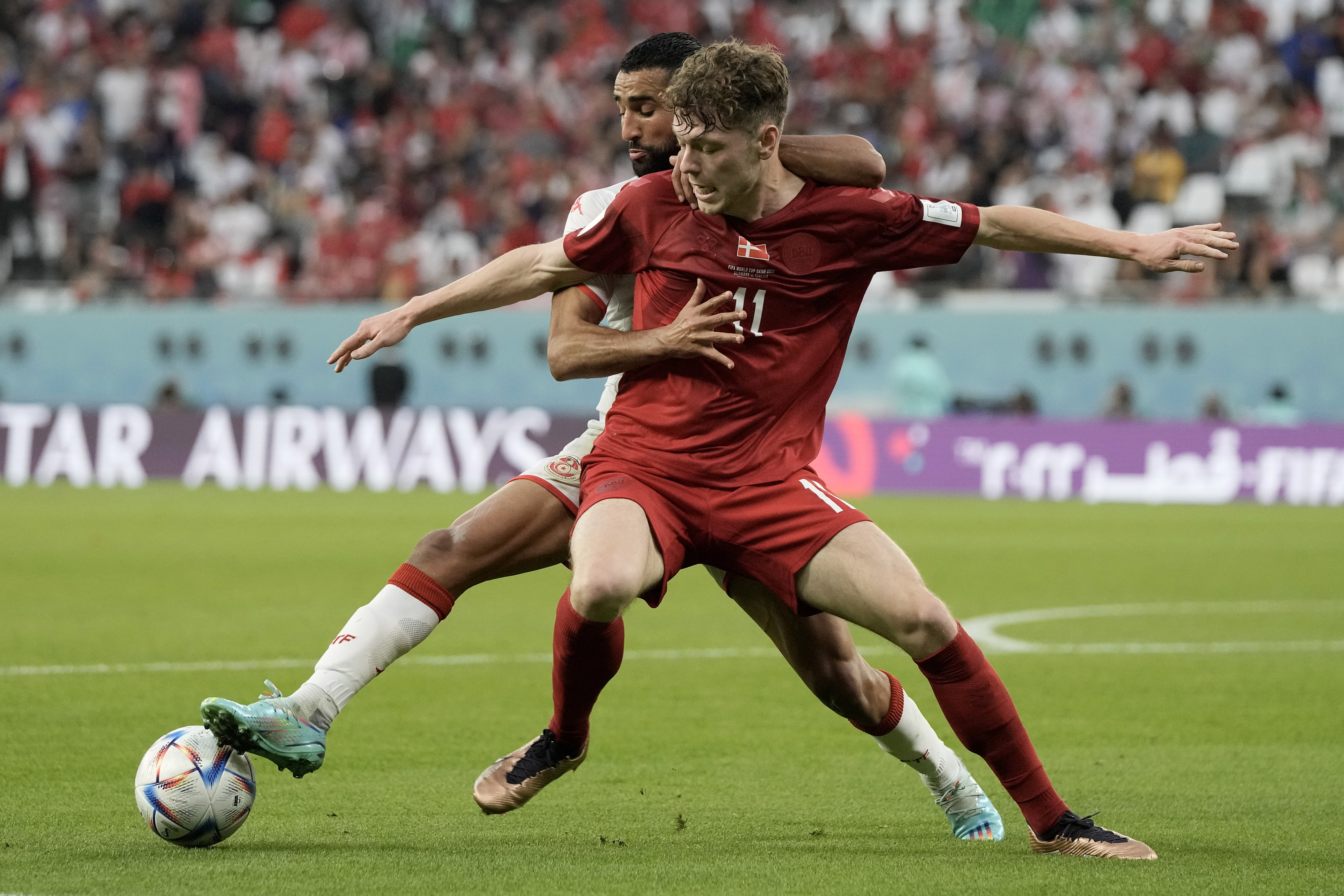 Tunisia’s Ali Abdi, rear, and Denmark’s Andreas Skov Olsen challenge for the ball in what was a physical first match for Denmark