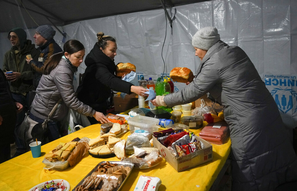 A volunteer distributes free food to people who lost electrical power after recent Russian attacks, in a heating point in the town of Vyshhorod, north of Kyiv, Ukraine, Friday, Nov. 25, 2022. (AP Photo/Efrem Lukatsky)