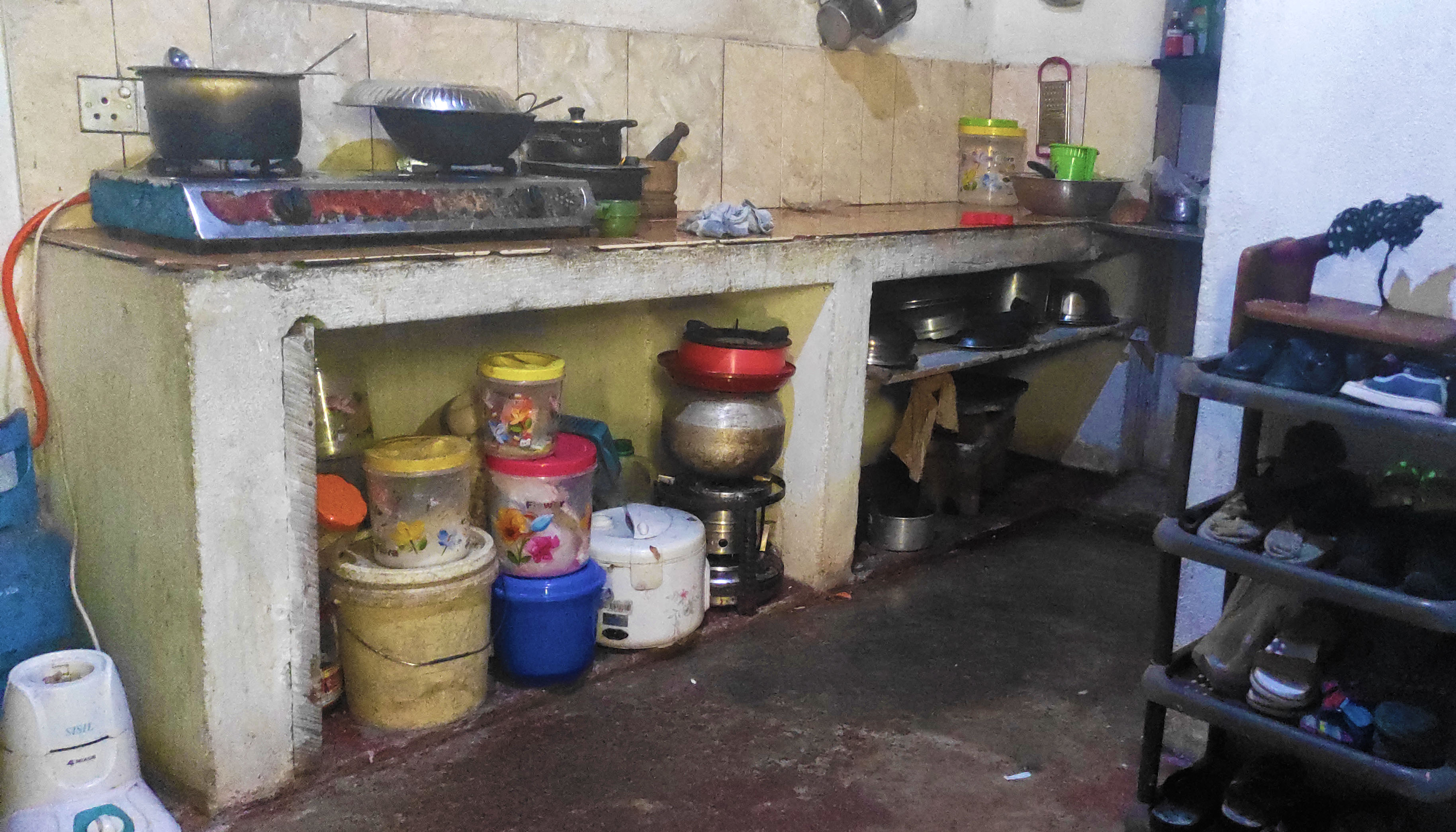 A poorly ventilated portion of the house is used as a shared space for a kitchen and a washroom