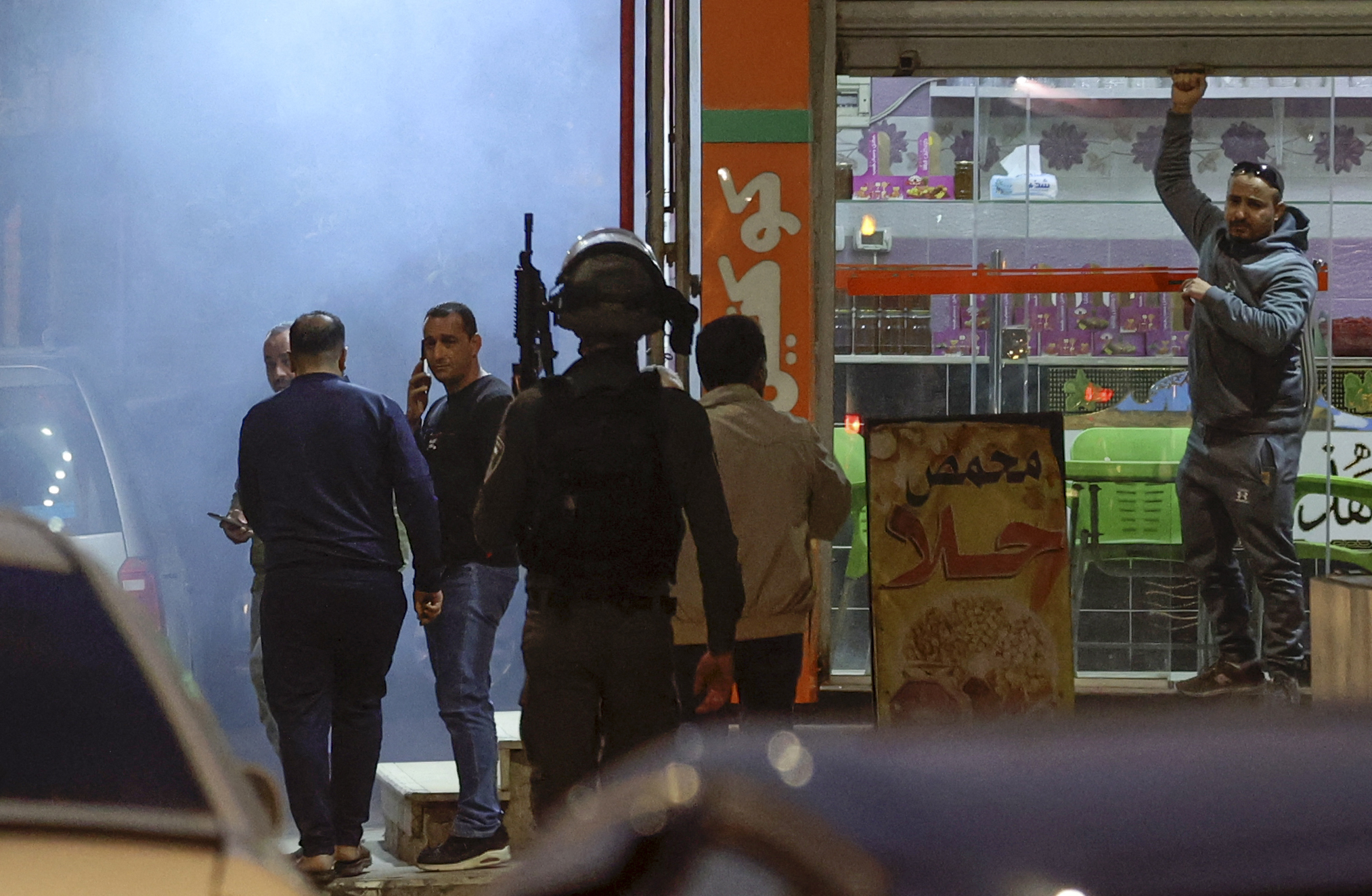 A Palestinian man shuts his shop as Israeli security forces deploy in the occupied West Bank town of Huwara