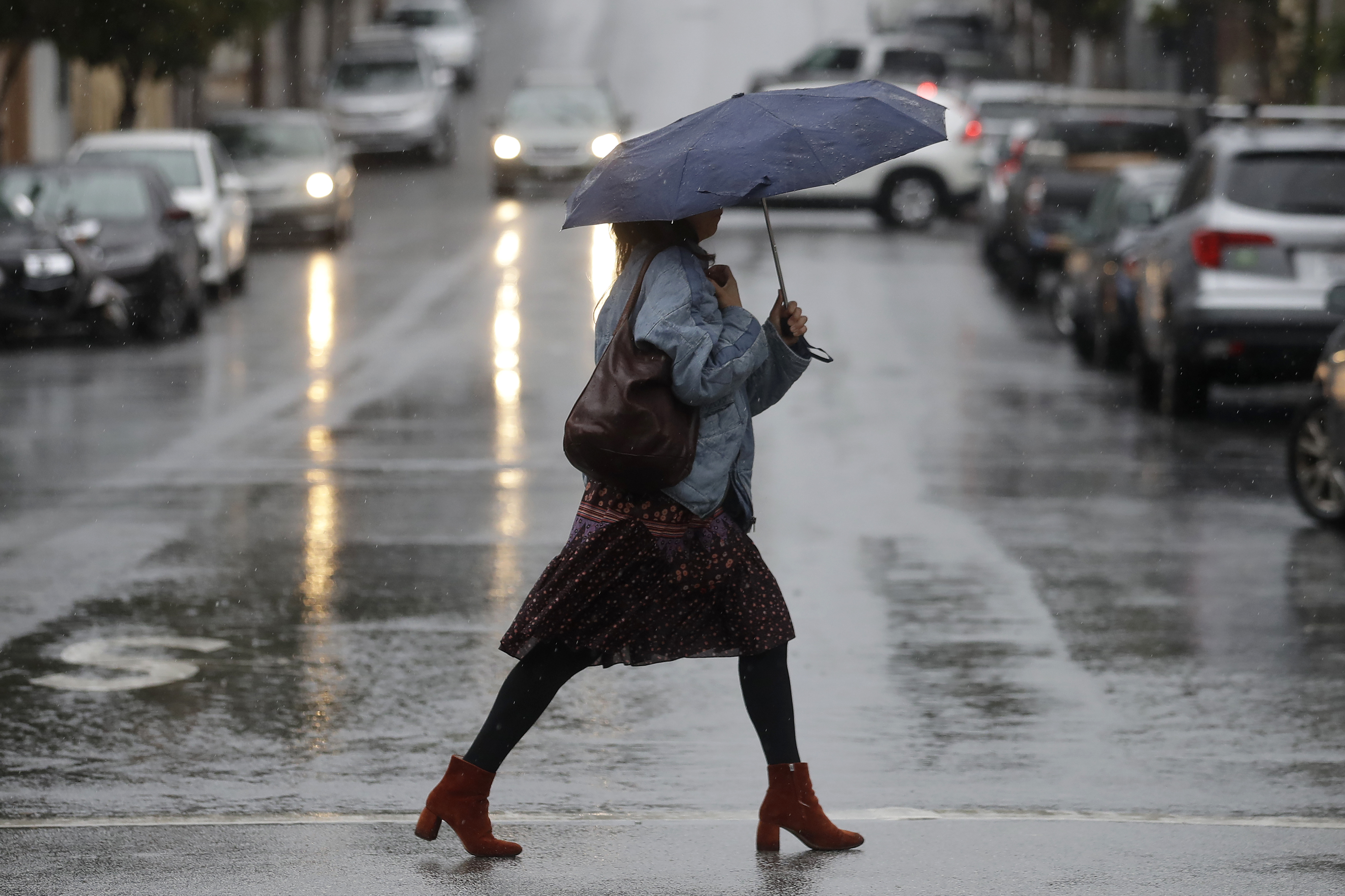 A woman walks in the rain in San Francisco, November 26, 2019, after northern California and southern Oregon residents were warned to brace for a ‘bomb cyclone’