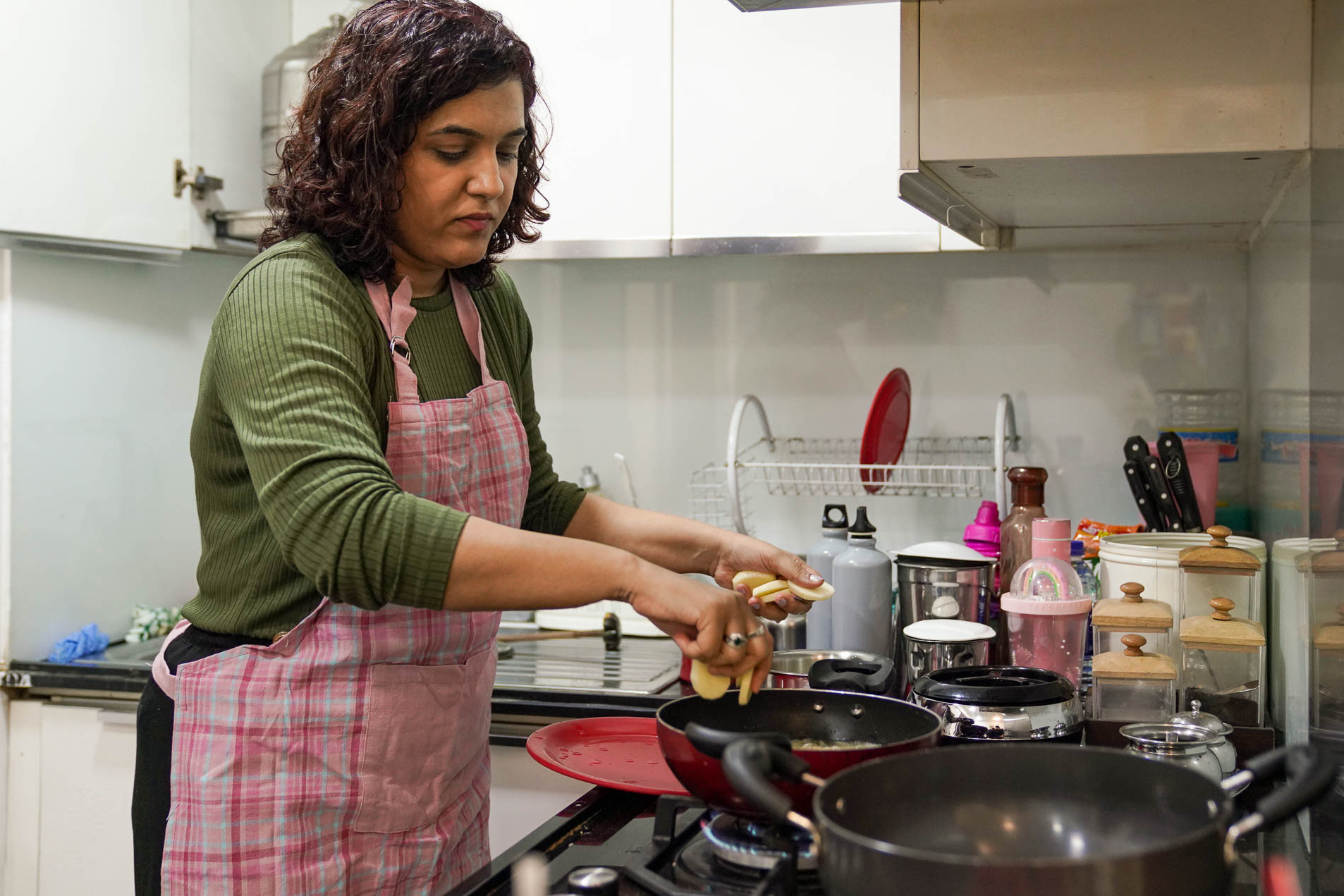 Khushboo drops sliced potatoes into a pan to prepare the fried potatoes