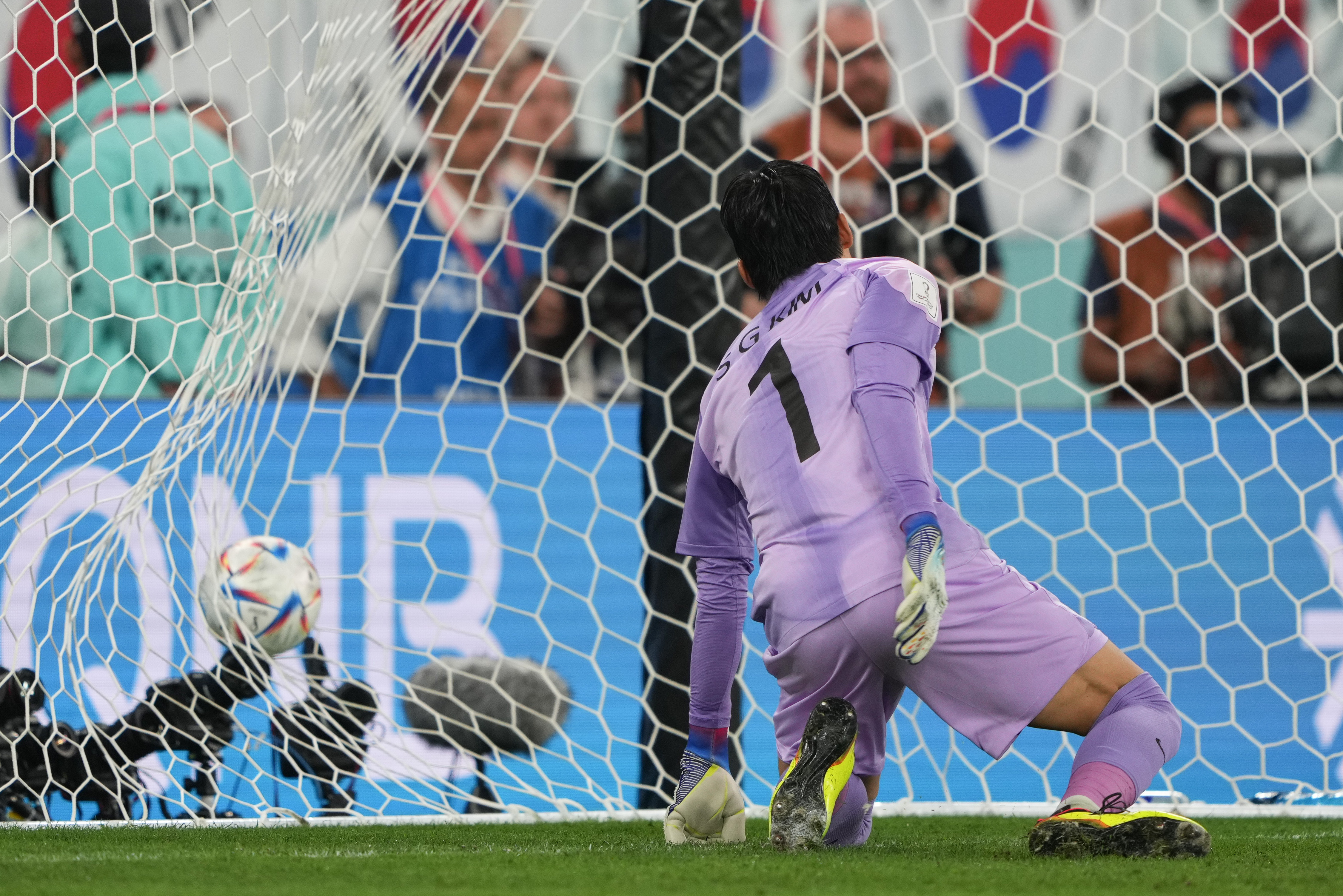 Kim Seung-gyu, on his knees, looks back to watch the ball enter his net after a penalty shot by Brazil's Richarlison.