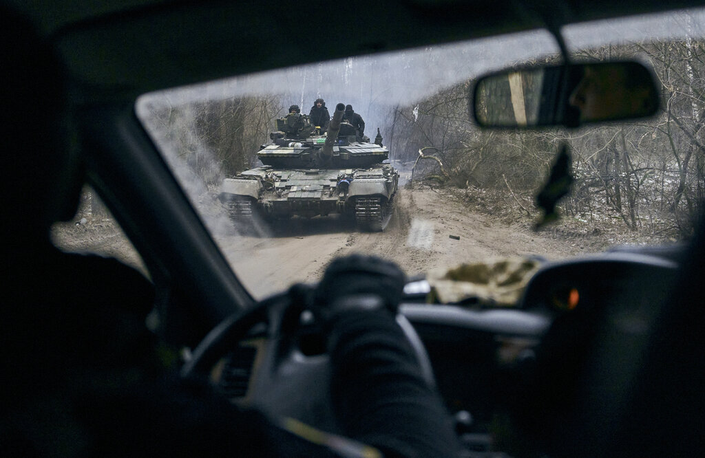 A Ukrainian tank with soldiers is seen through a car window close to the frontline near Kremenna in the Luhansk region, Ukraine, Sunday, Jan. 15, 2023. (AP Photo/LIBKOS)