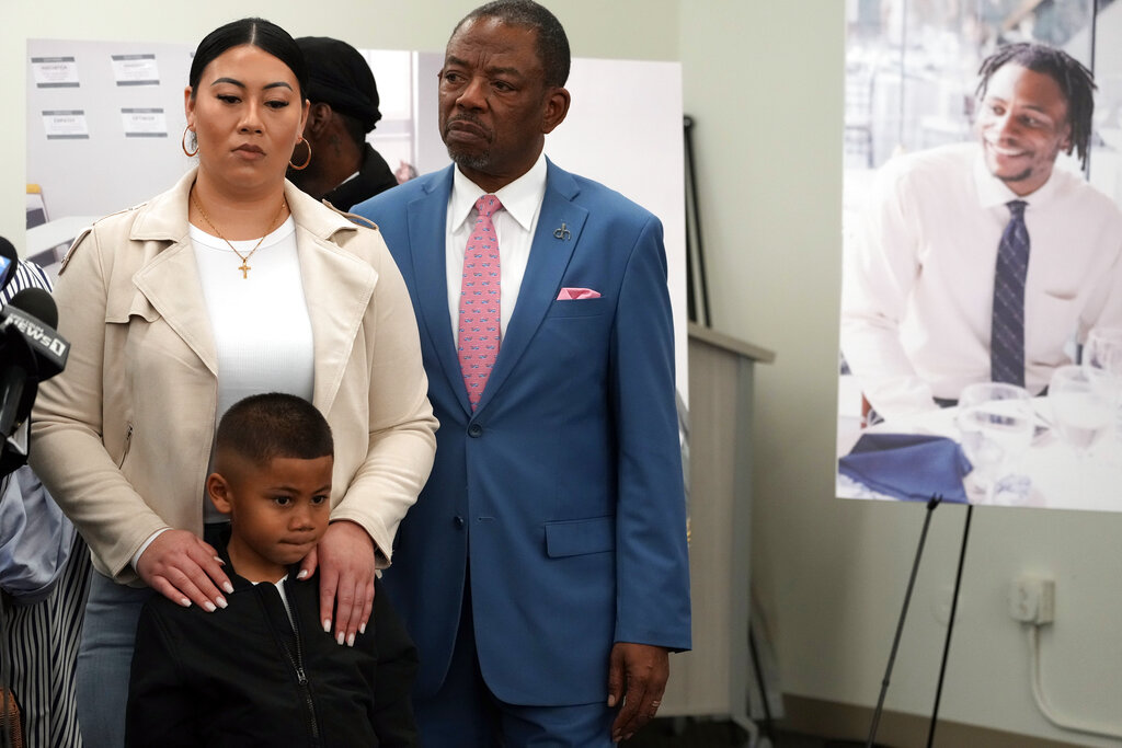 A lawyer stands with Anderson's son and his guardian at a press conference