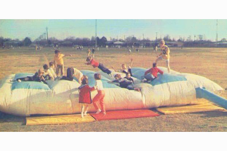 A photo of children playing on a moon bounce or space pillow.