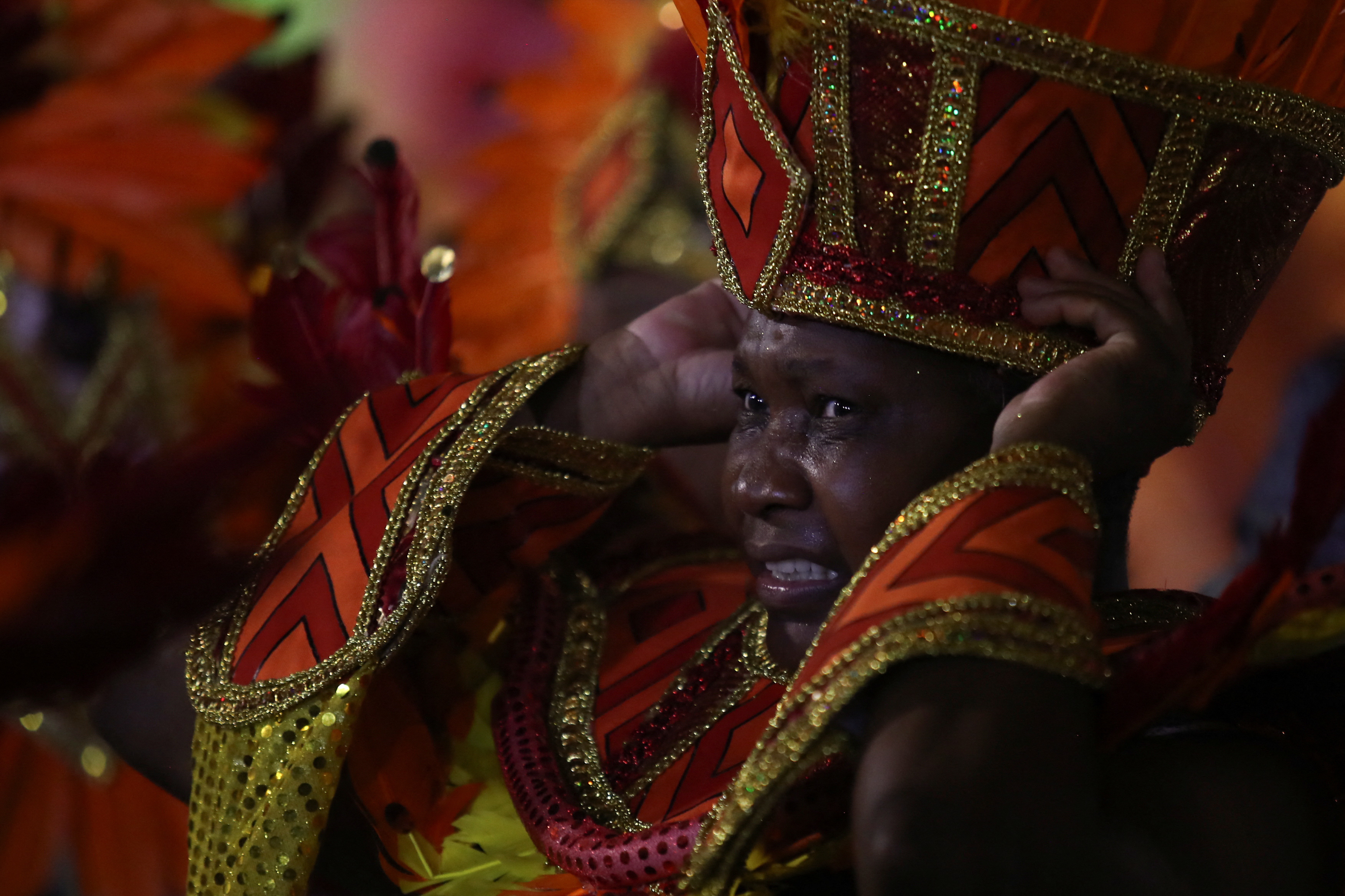 A reveller adjusts her tall, decorative hat