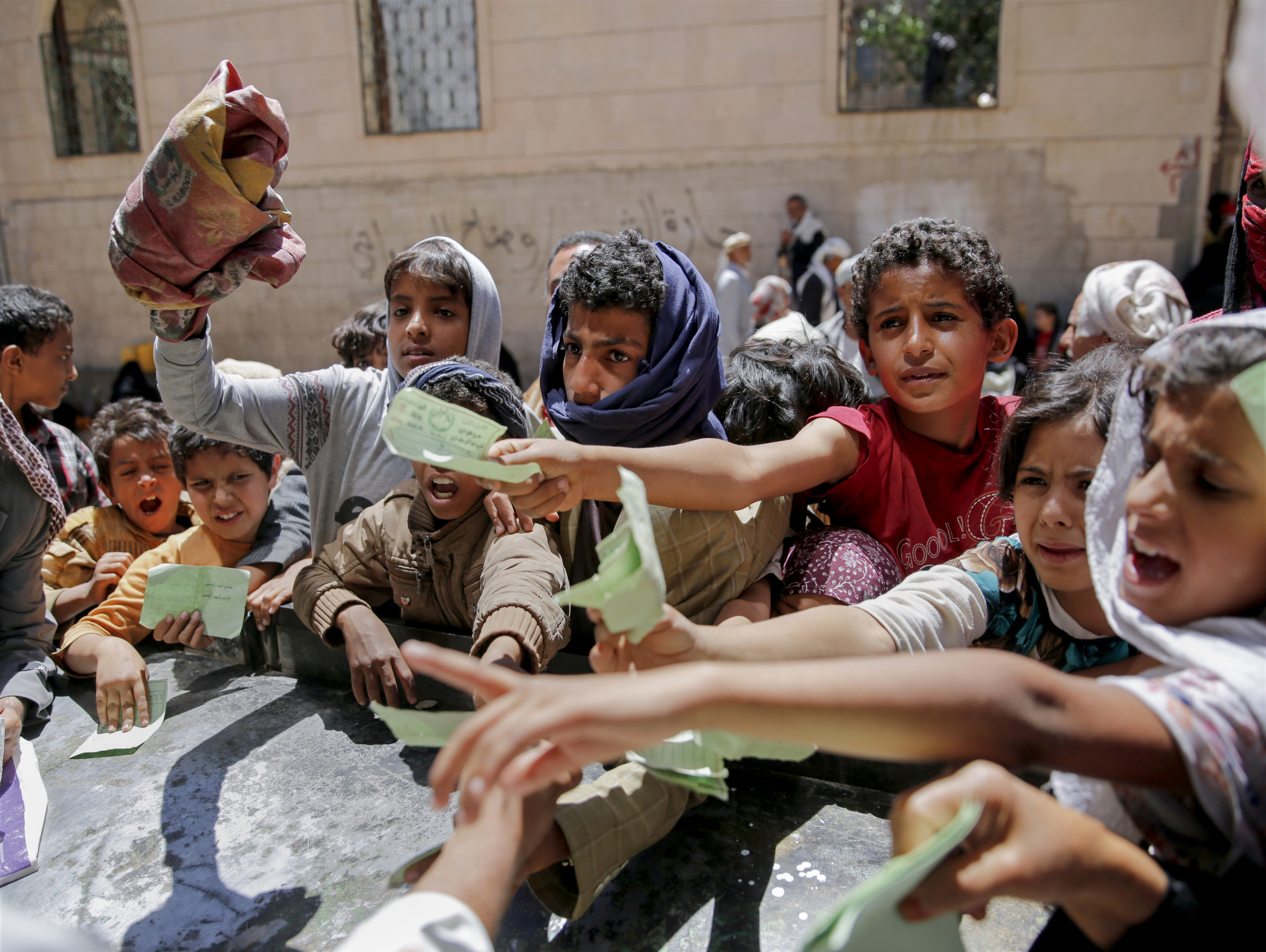 Yemenis present documents in order to receive food rations provided by a local charity, in Sanaa
