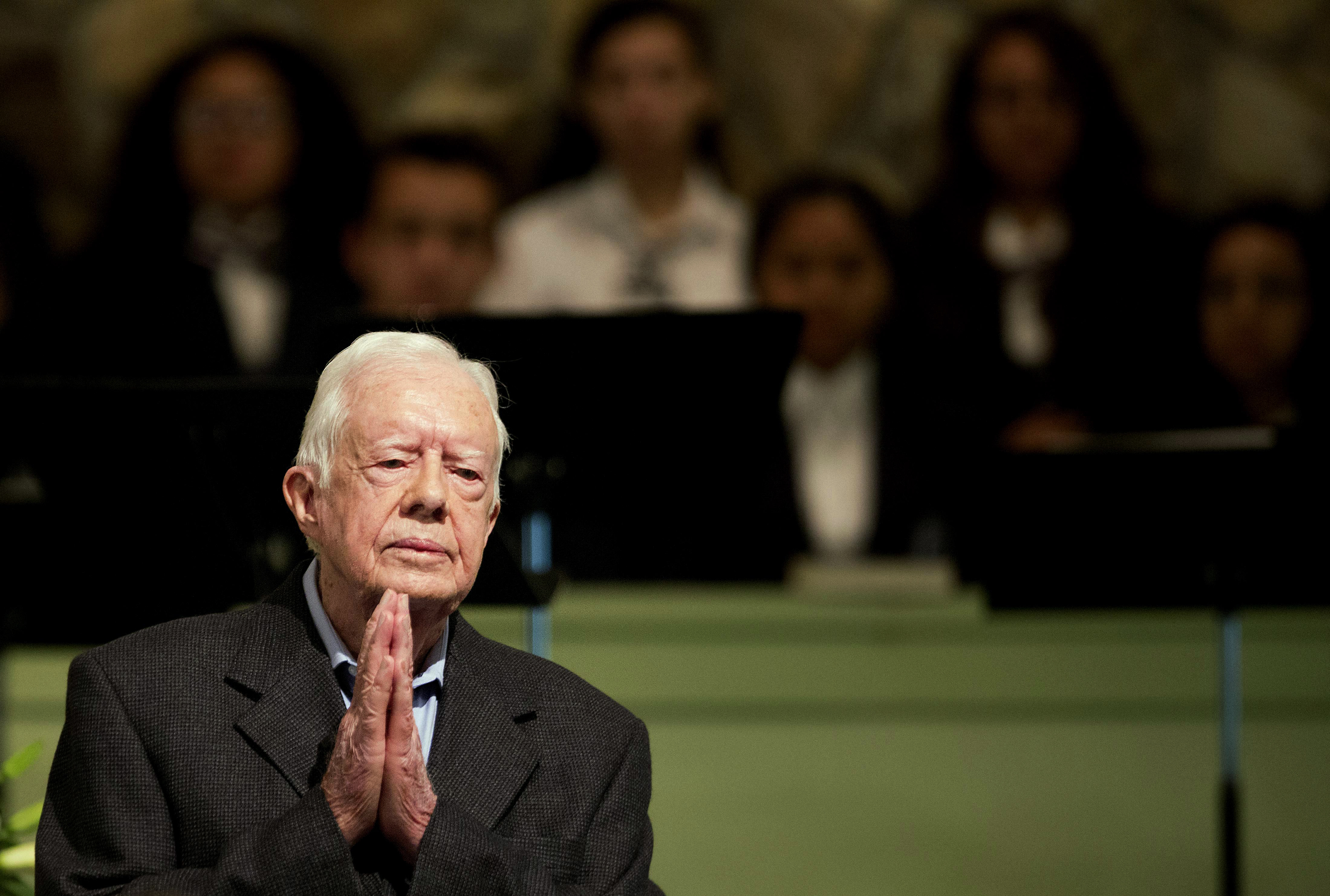 Jimmy Carter holds his hands together in prayer
