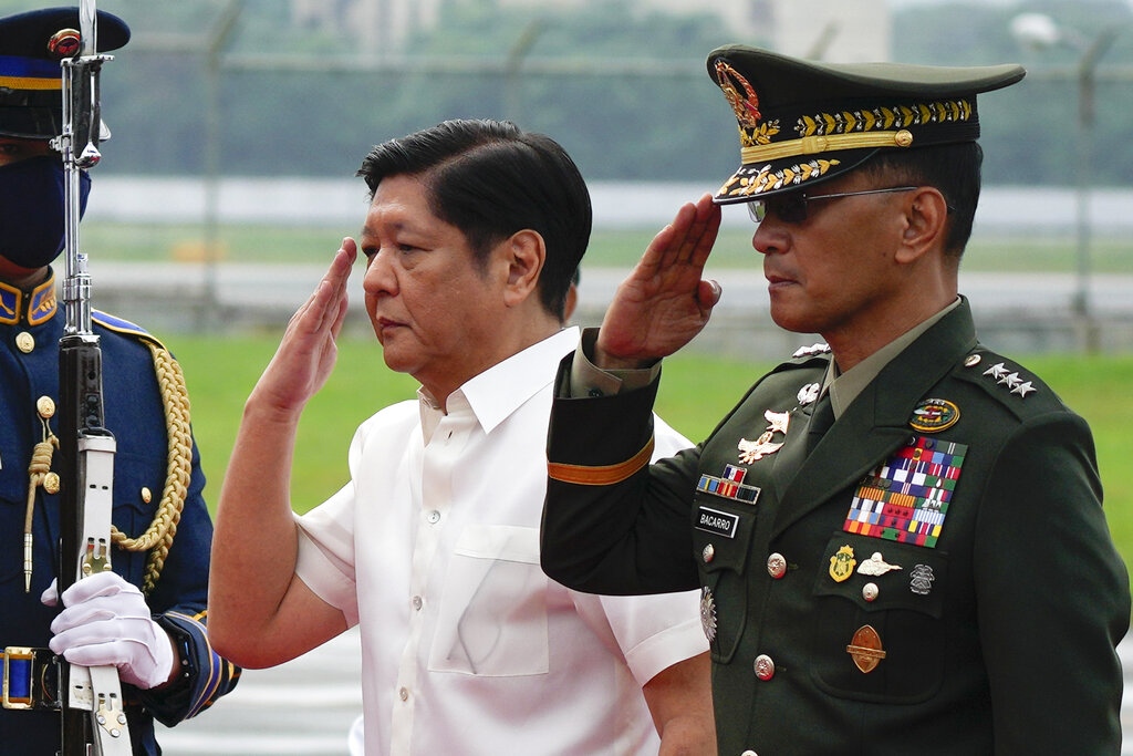 Philippine President Ferdinand Marcos Jr. salutes with Philippine military chief Lt. Gen. Bartolome Vicente Bacarro before departing to Beijing on Jan. 3, 2023, at the Villamor Air Base in Metro Manila, Philippines. Marcos Jr. on Saturday Jan. 7 cut short the term of Lt. Gen Bacarro, whom he appointed five months ago, and replaced him with a retiring general without explaining the surprise move. (AP Photo/Aaron Favila, File)