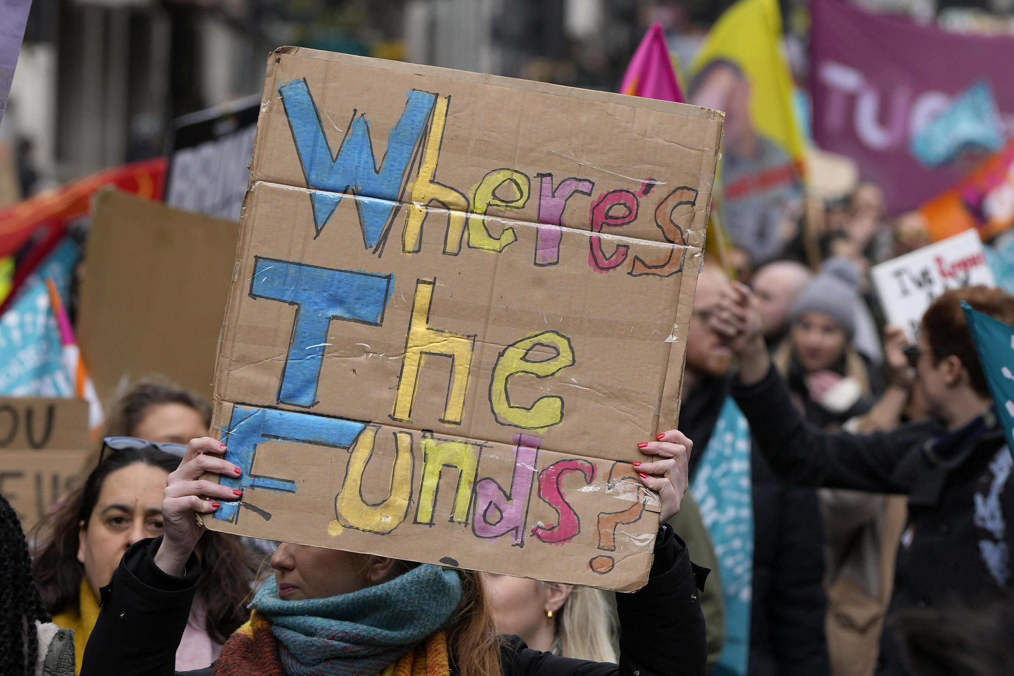 Striking teachers show posters during a protest march in London, Wednesday, Feb. 1, 2023. Thousands of schools in the U.K. are closing some or all of their classrooms, train services will be paralyzed and delays are expected at airports Wednesday in what's shaping up to be the biggest day of industrial action Britain has seen in more than a decade, as unions step up pressure on the government to demand better pay amid a cost-of-living crisis.(AP Photo/Alastair Grant)