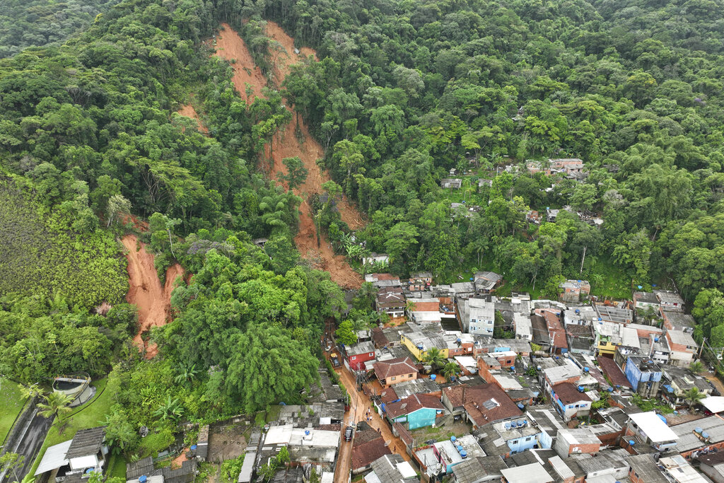 The side of a hill shows scars from flooding with a town below