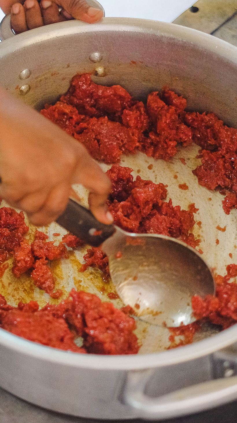 A chef moves ground kitfo quickly around a pot to prepare for a customer