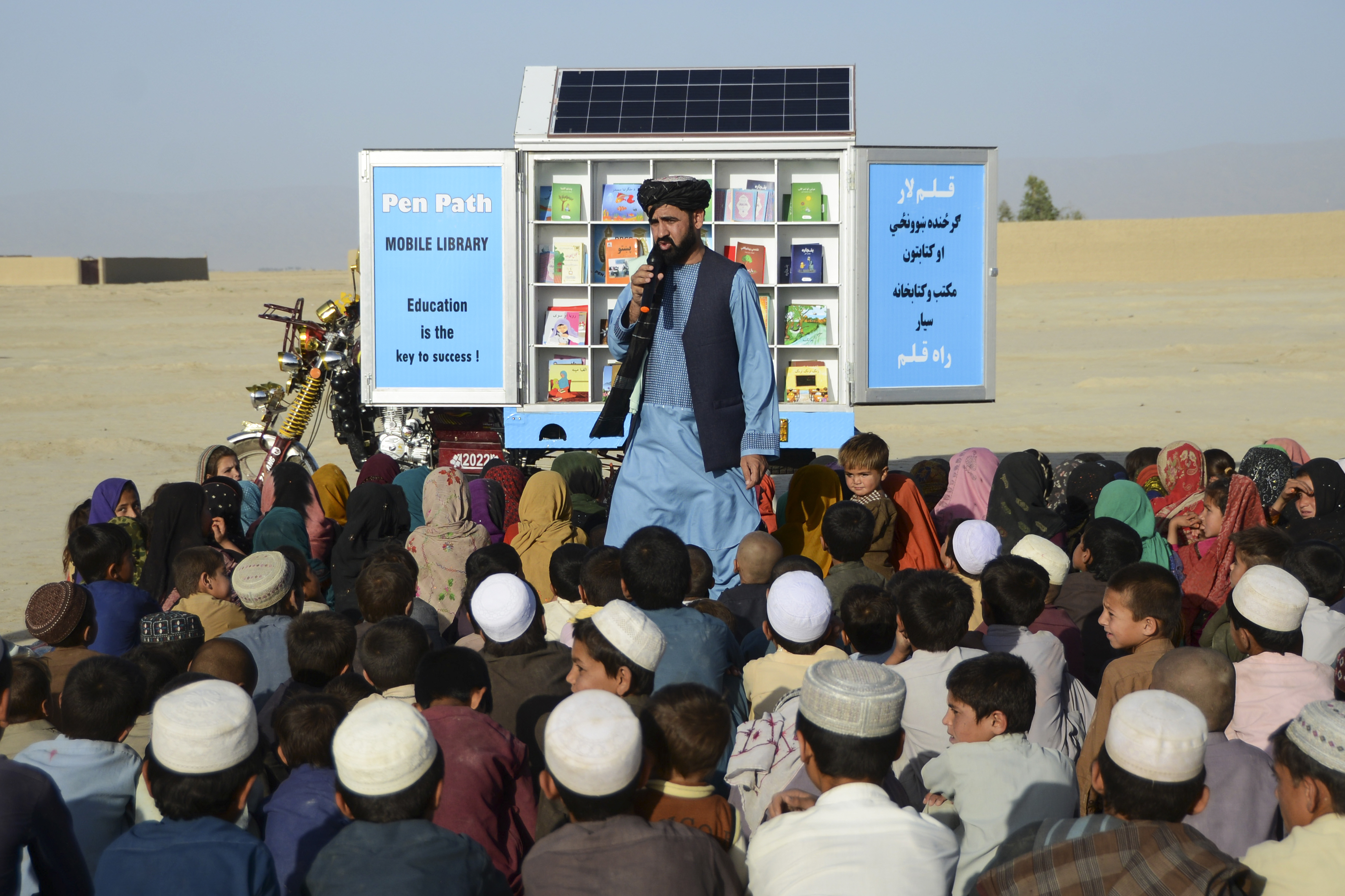 In this photograph taken on May 17, 2022, Matiullah Wesa, head of Pen Path and advocate for girls’ education in Afghanistan, speaks to children during a class next to his mobile library in Spin Boldak district of Kandahar Province