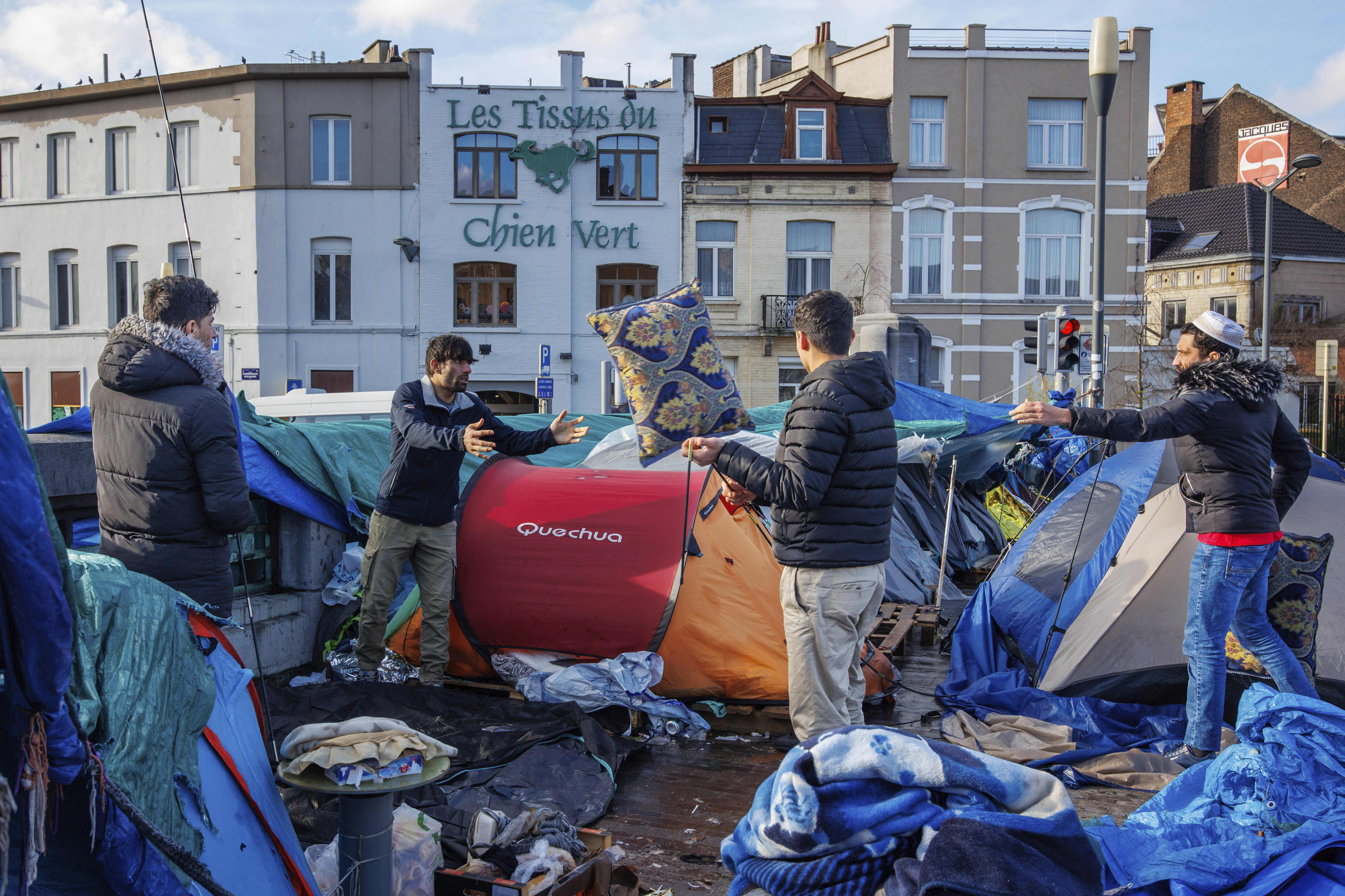 Men organize their belongings at a makeshift tent camp outside the Petit Chateau reception center in Brussels, Tuesday, Jan. 17, 2023. Many refugees and asylum-seekers are literally left out in the cold for months as the European Union fails to get its migration system working properly. And most talk is about building fences and repatriation instead of working to improve a warm embrace for people fleeing nations like Afghanistan where the Taliban has taken over. (AP Photo/Olivier Matthys)