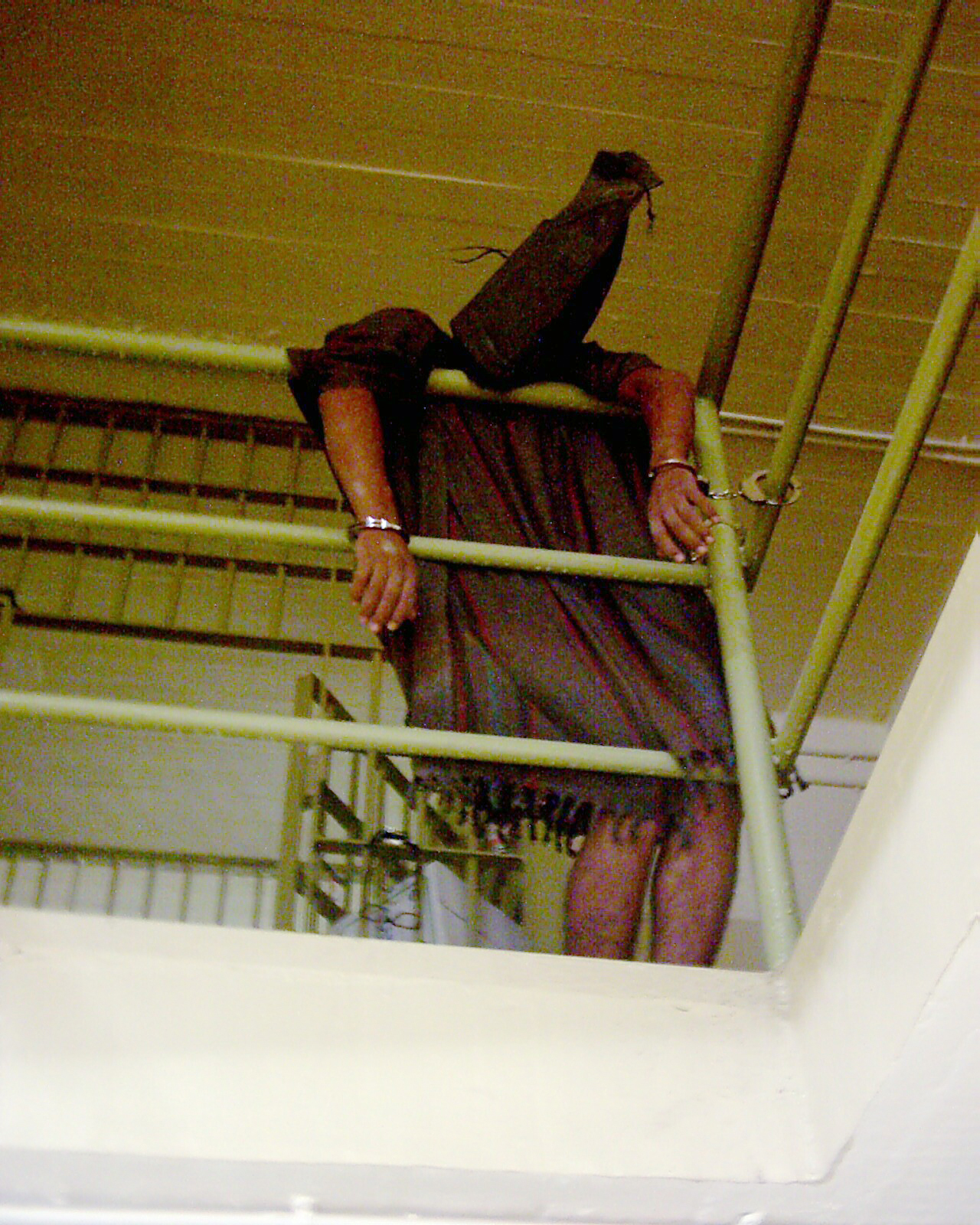 A detainee handcuffed to a railing with a bag over his head in late 2003 at Abu Ghraib prison in Baghdad, Iraq