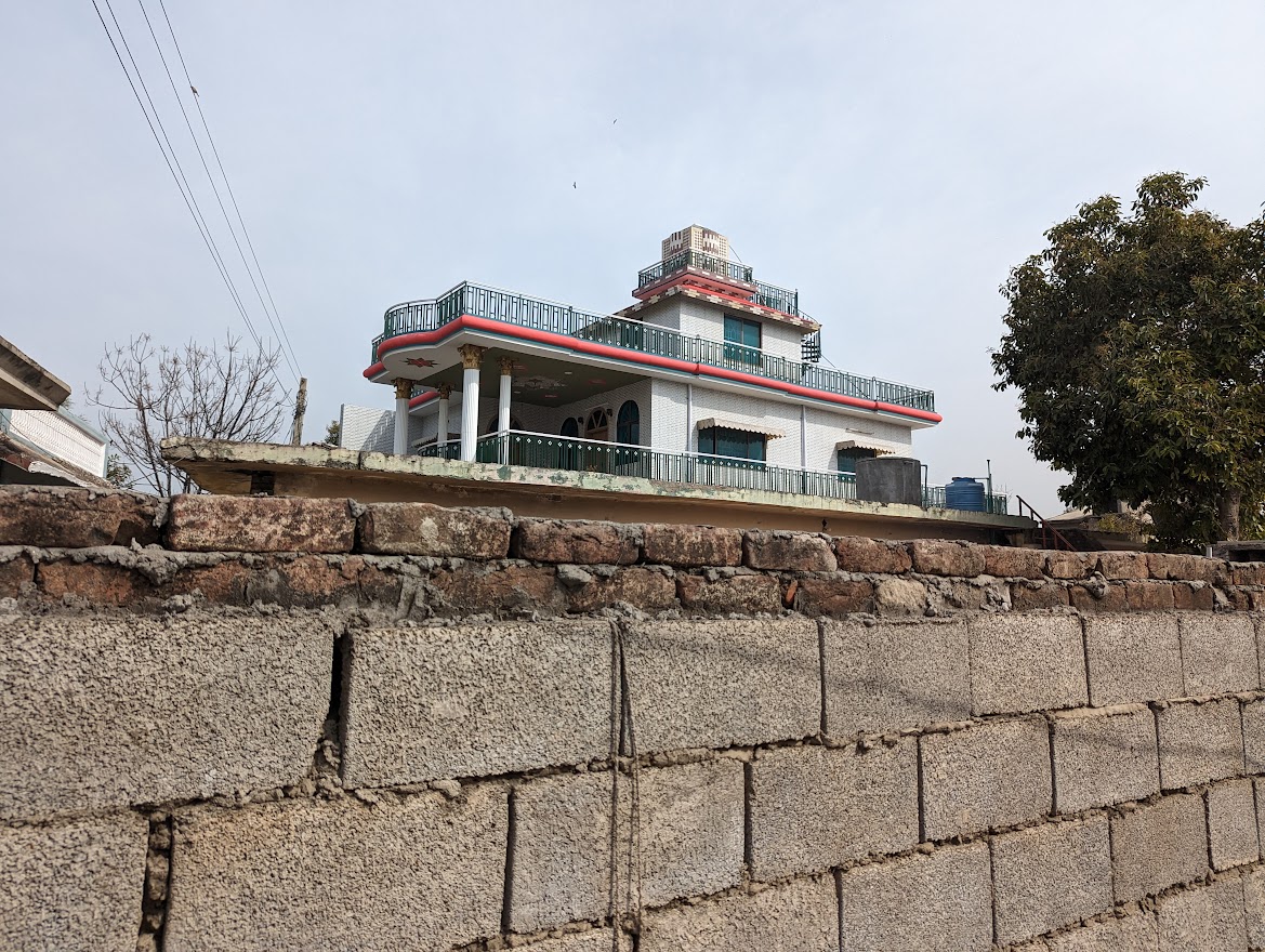 A photo of a multi-story house behind a wall.