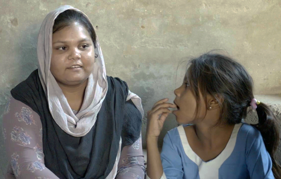 A photo of a woman on the left sitting with a child on the right.
