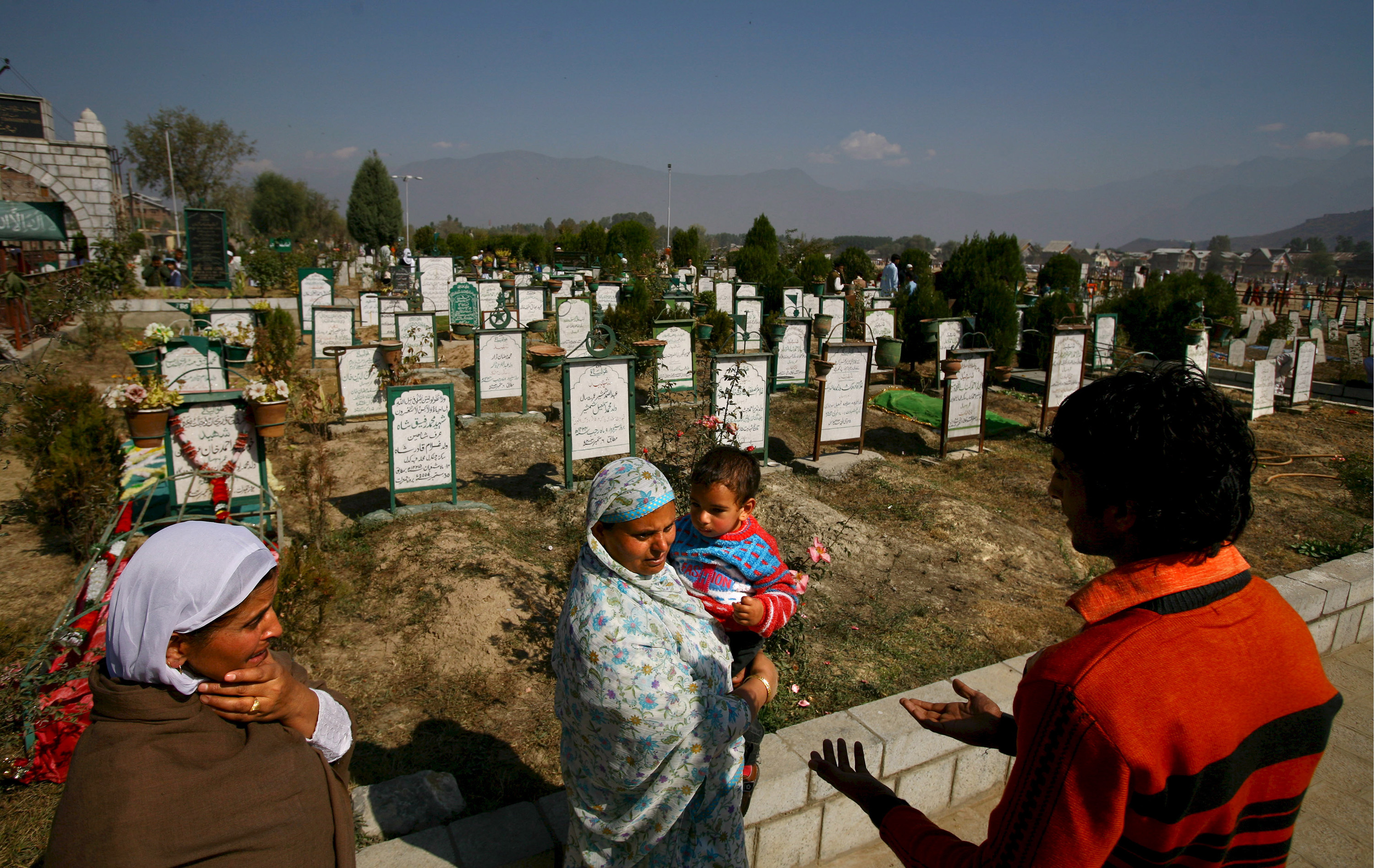 A Kashmiri family visits the grave of their relative at a graveyard during Eid-al-Fitr celebrations in Srinagar [File: EPA Images]