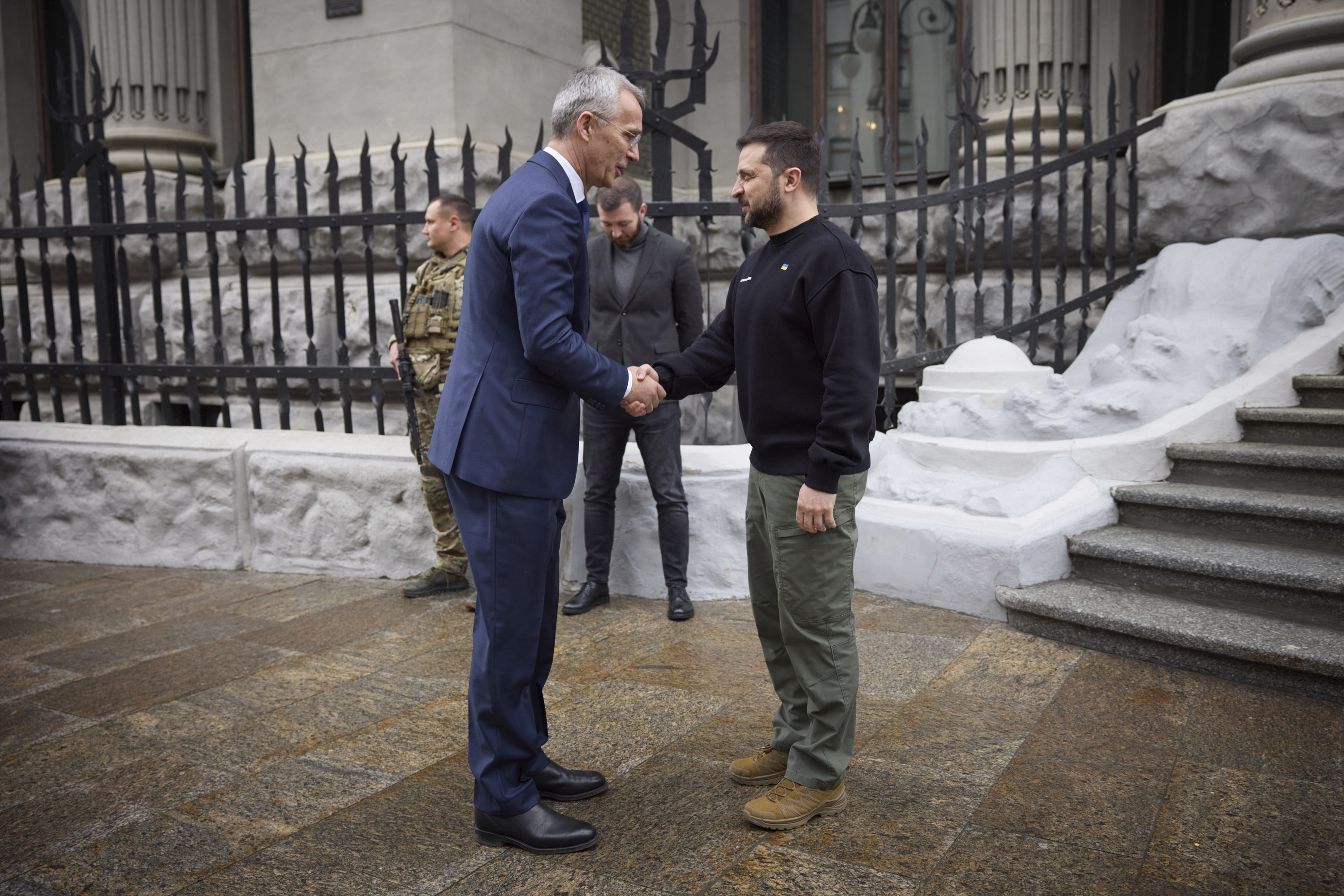 Jens Stoltenberg and Volodymyr Zelenskyy shaking hands on the street in Kyiv
