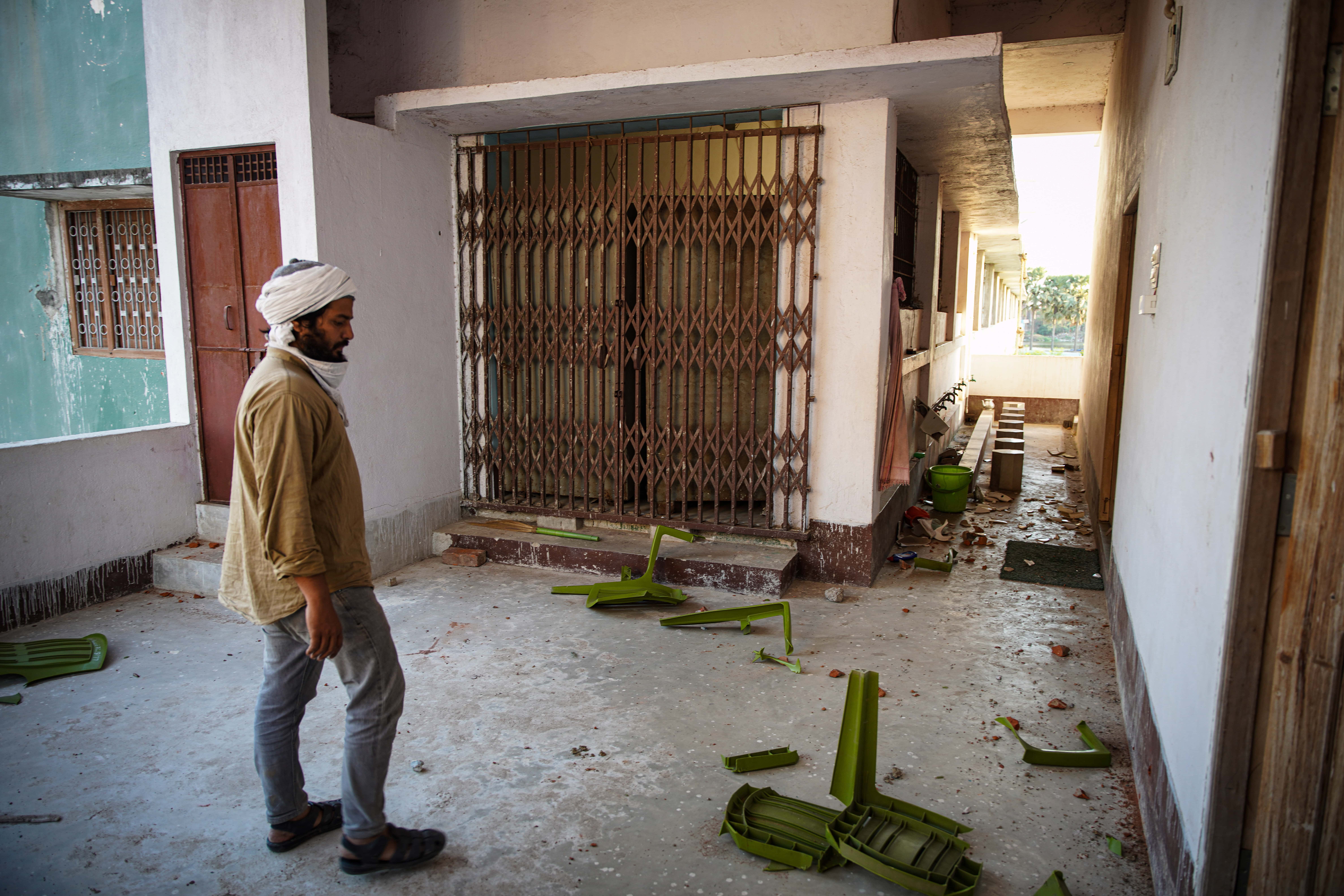 A man looks at broken chairs inside a mosque in Bihar Sharif town