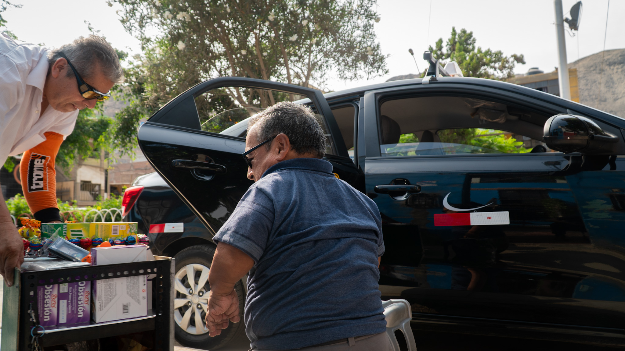 A taxi driver helps a street vendor in Peru